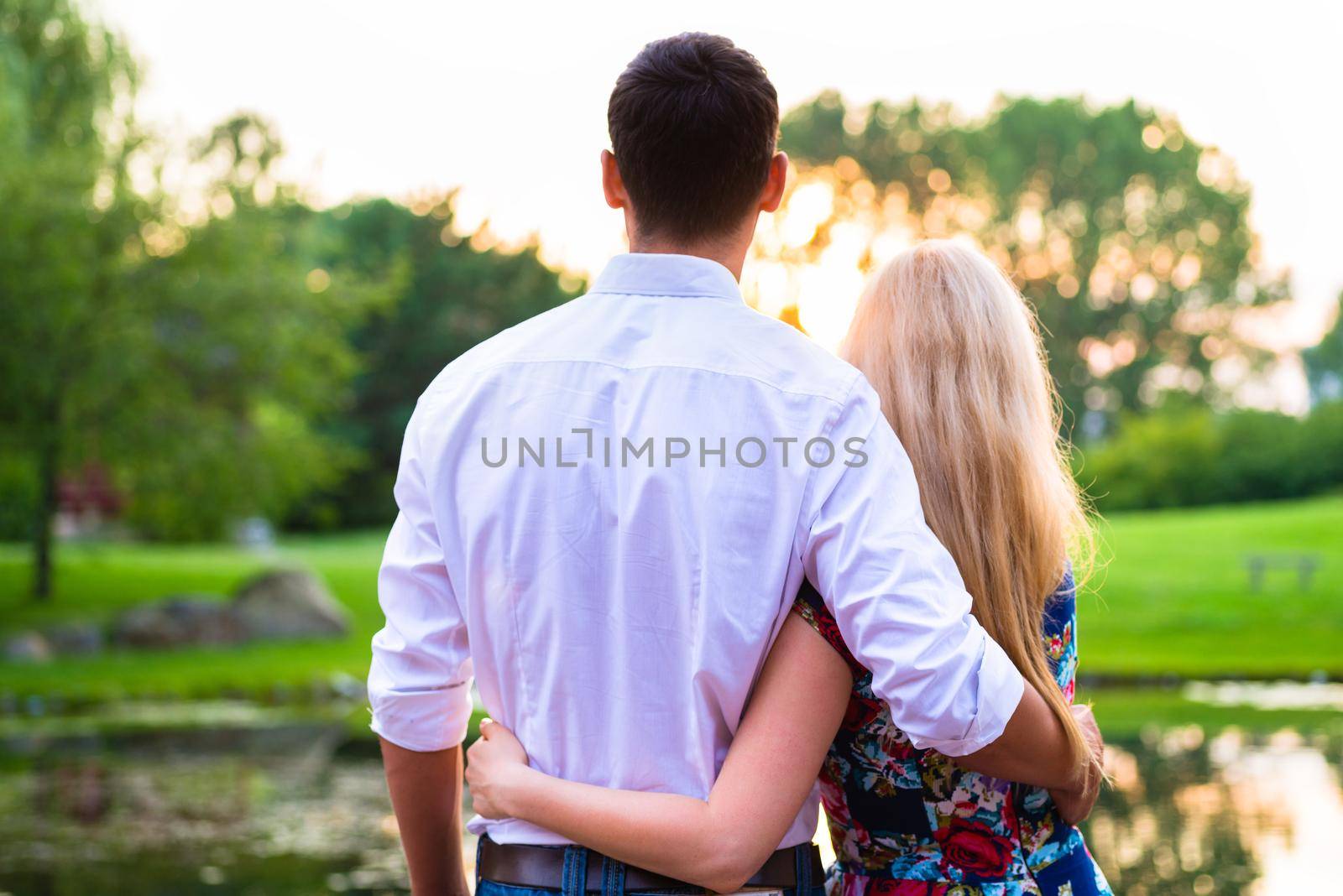 Couple dreaming their life together looking in romantic sunset, man embracing his girlfriend