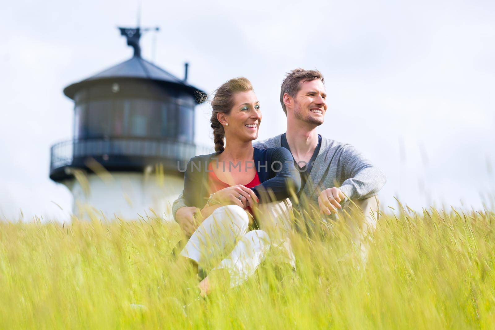 Couple enjoying holiday in front of lighthouse by Kzenon