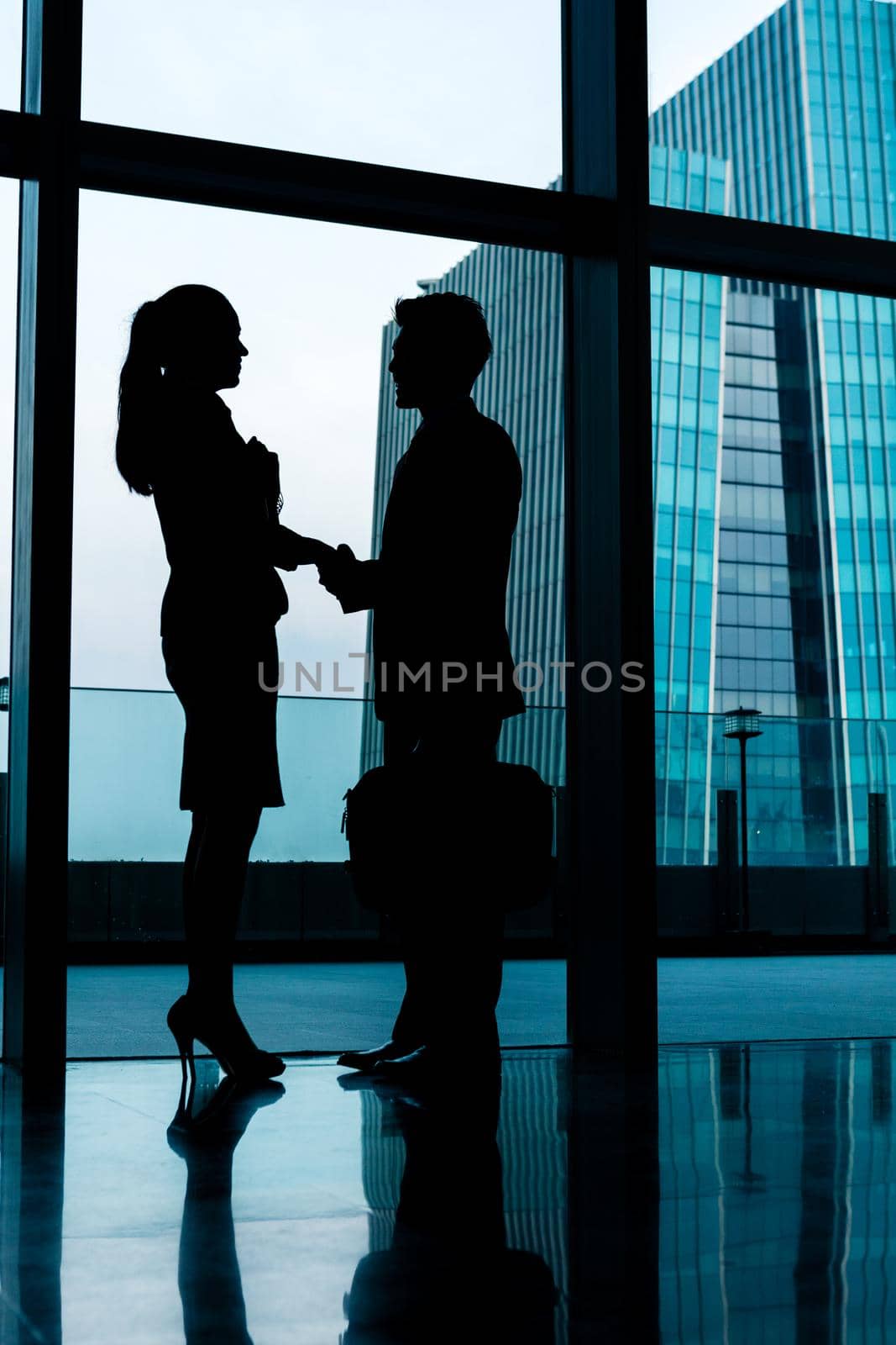Silhouettes of backlit business people handshake in front of city skyline