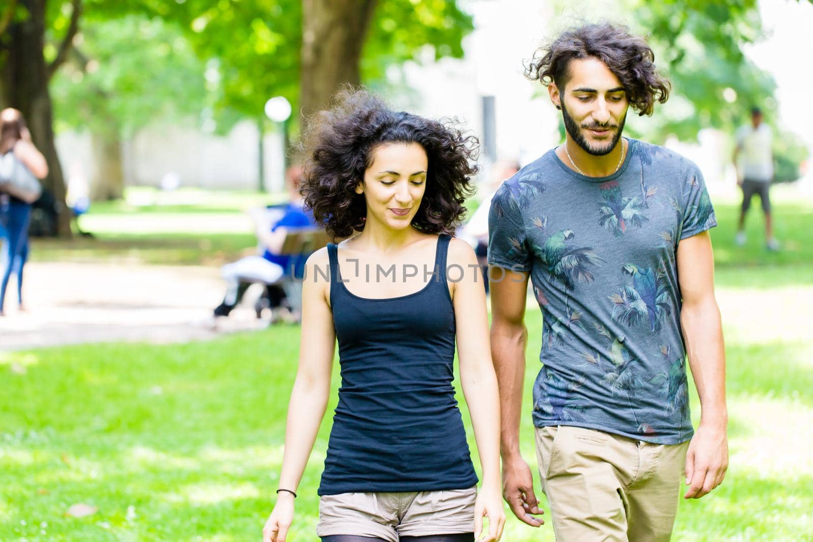 Couple, Latin man and woman, walking holding hands over meadow