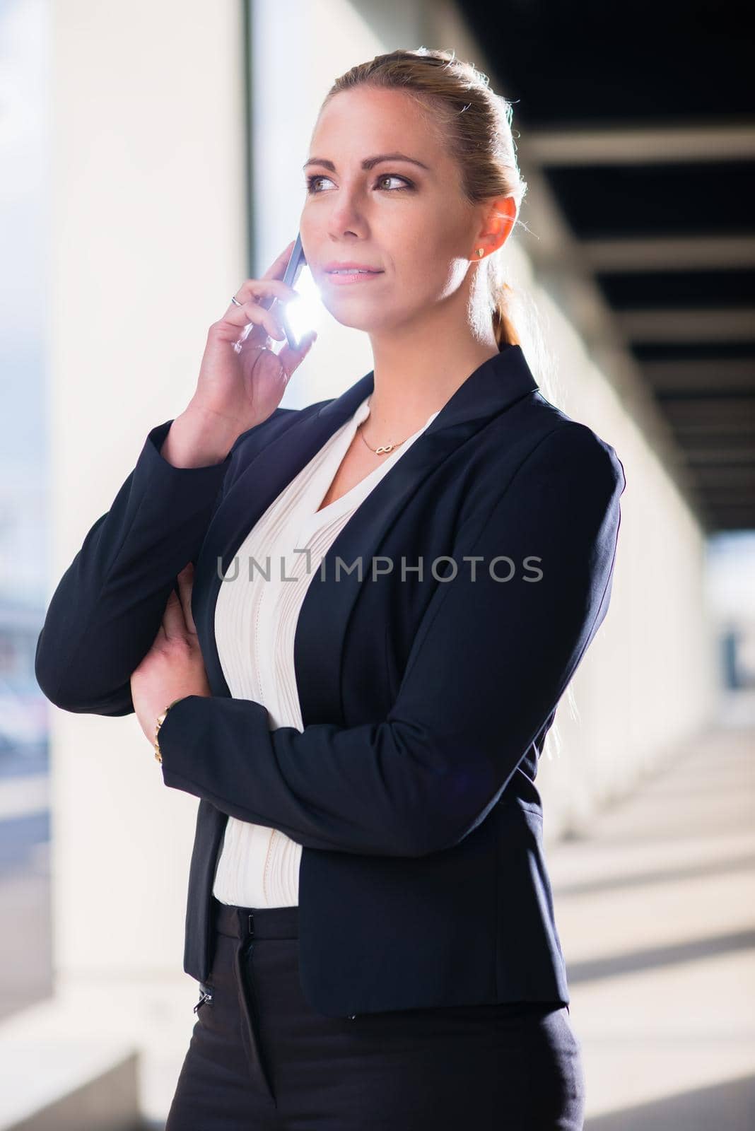 Business woman with phone outdoors standing in front of building