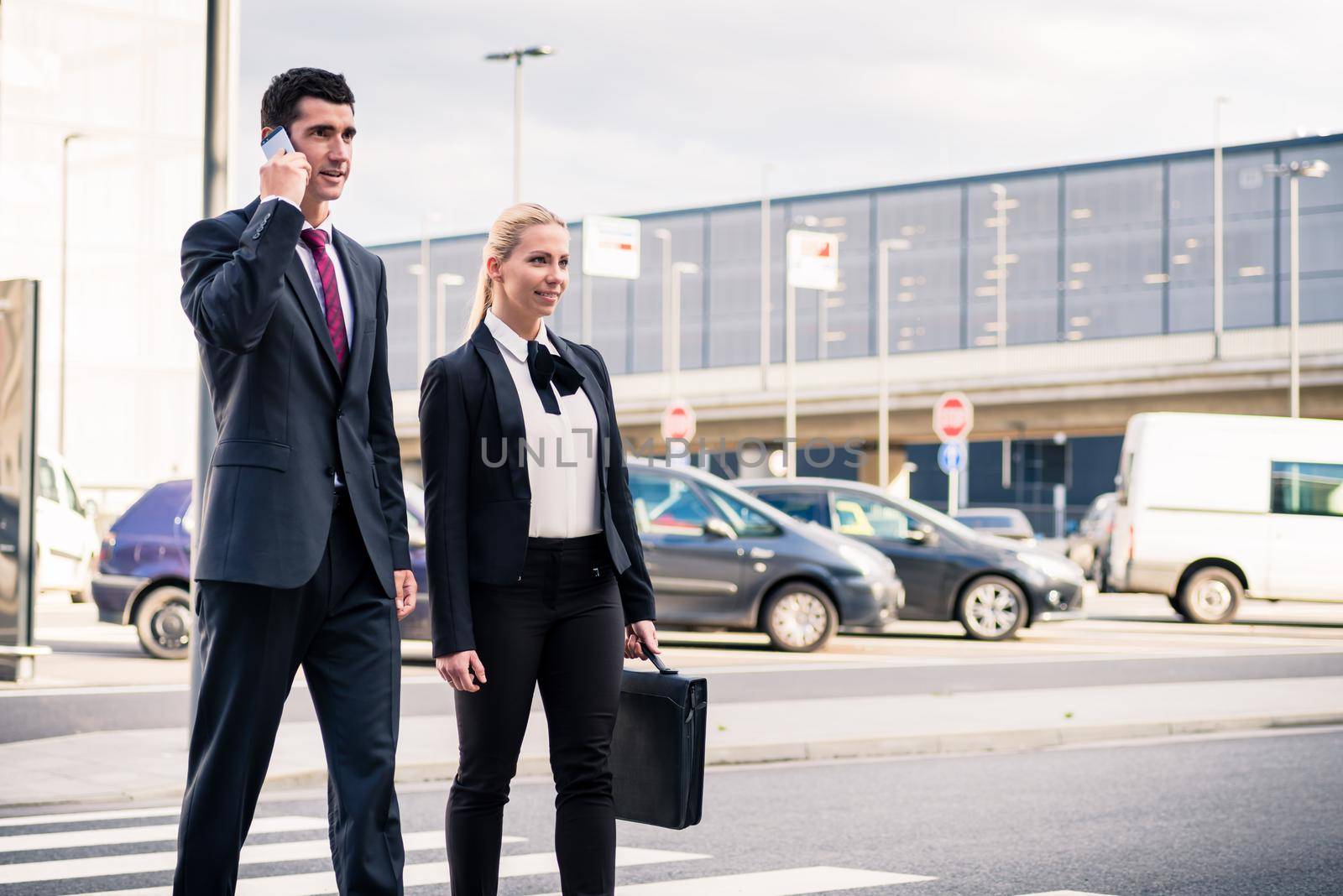 Business people at airport terminal travelling wearing briefcase and talking to smart phone