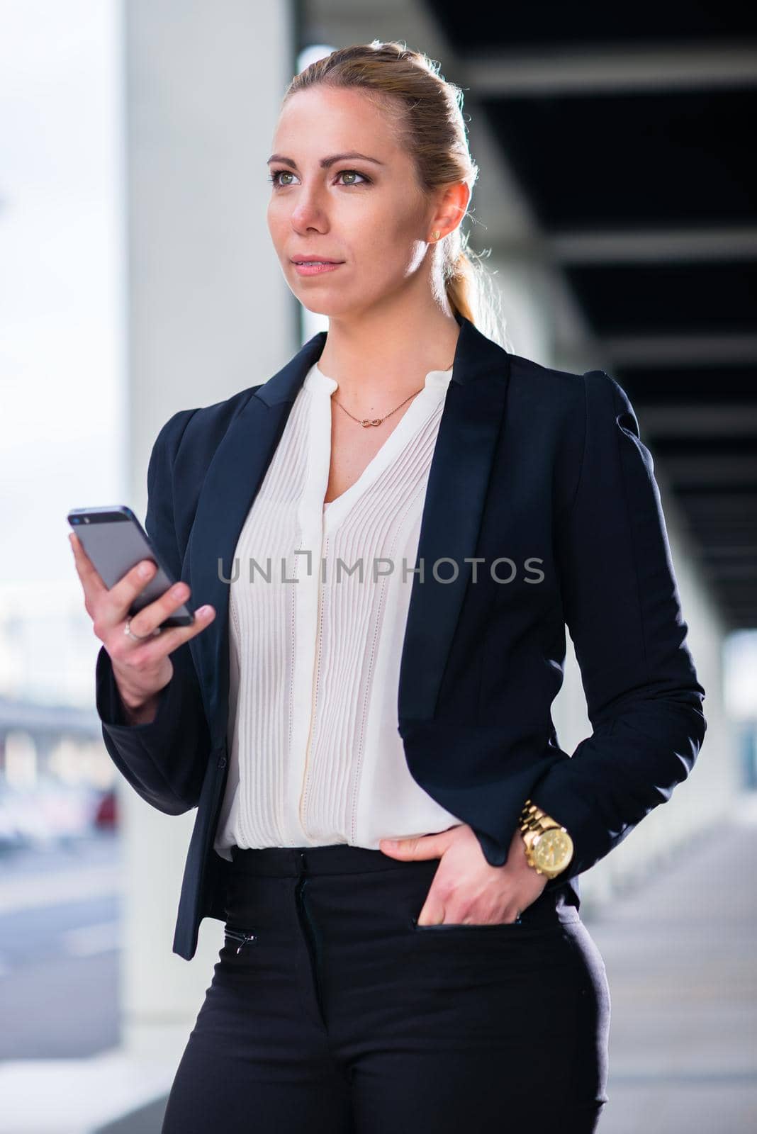 Business woman with phone outdoors standing in front of building