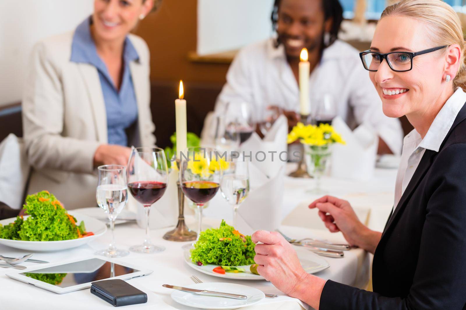 Team of business people eating in restaurant, food and wine on the table