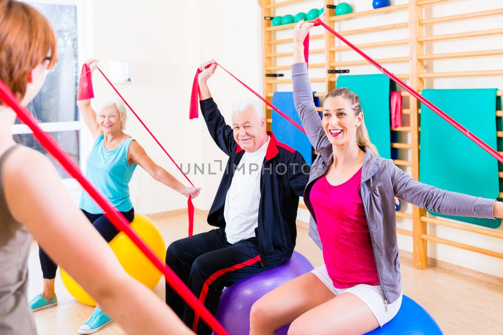 Senior people at fitness course in gym exercising with stretch band
