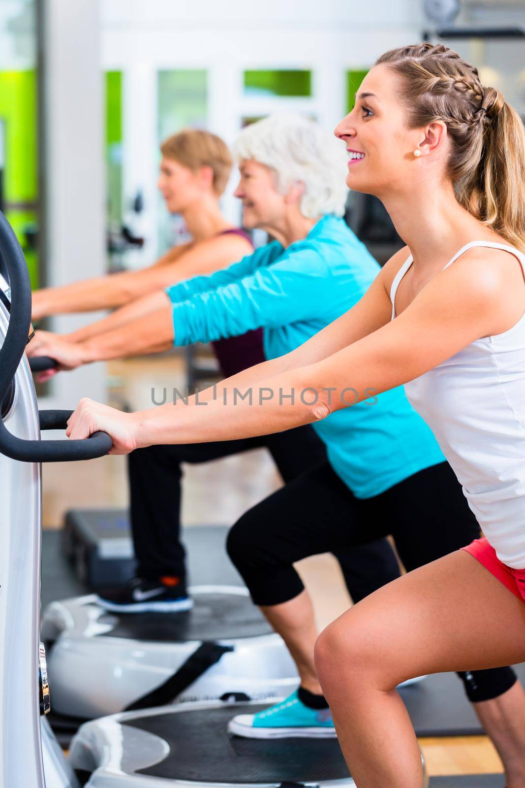 Group of people on vibrating plates in gym training