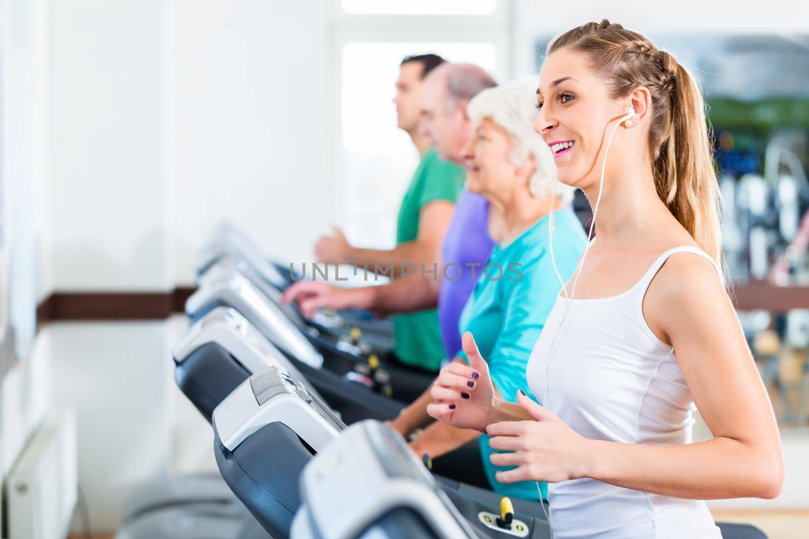 Group with senior and young men and women on treadmill in fitness gym running for sport