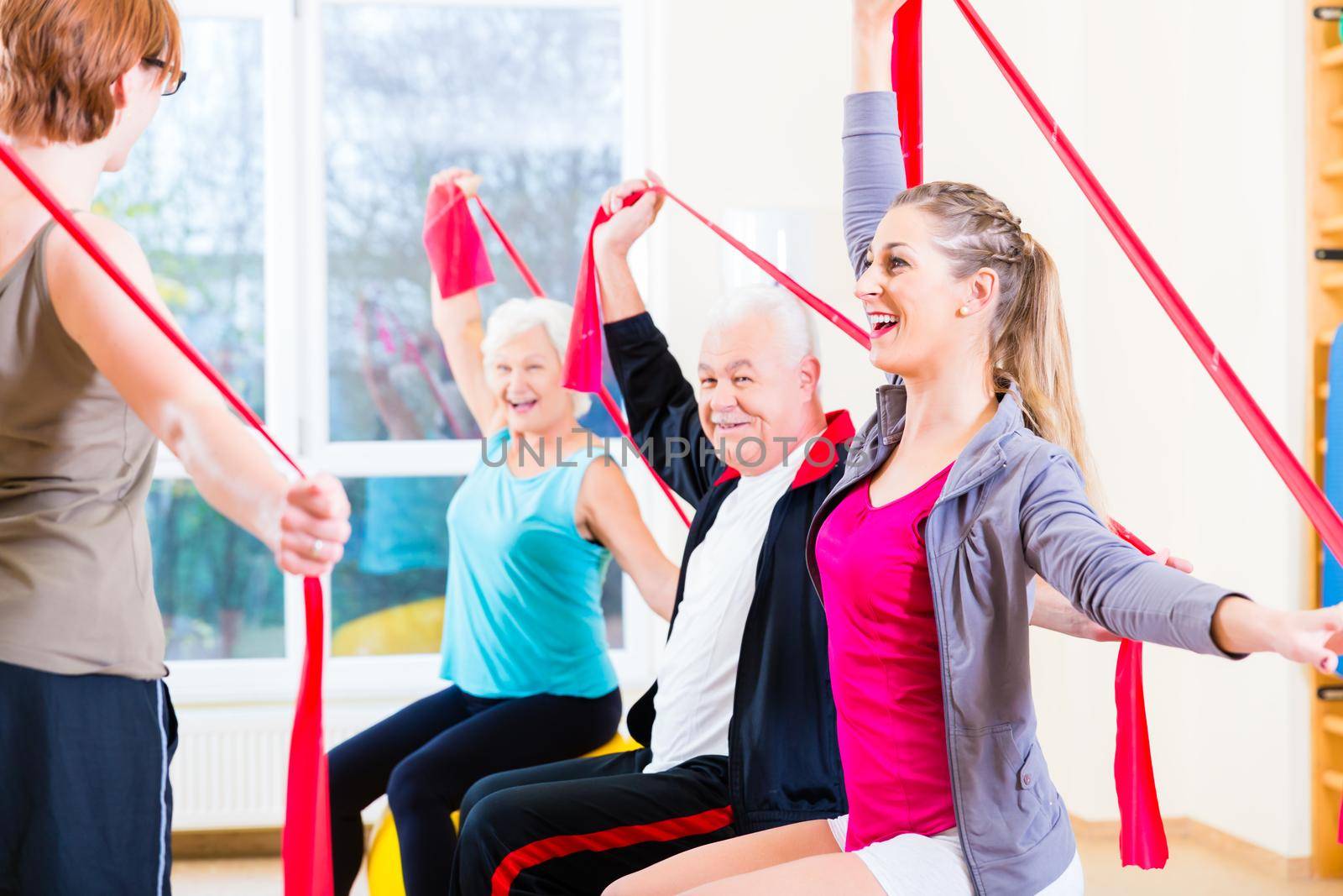 Senior people at fitness course in gym exercising with stretch band