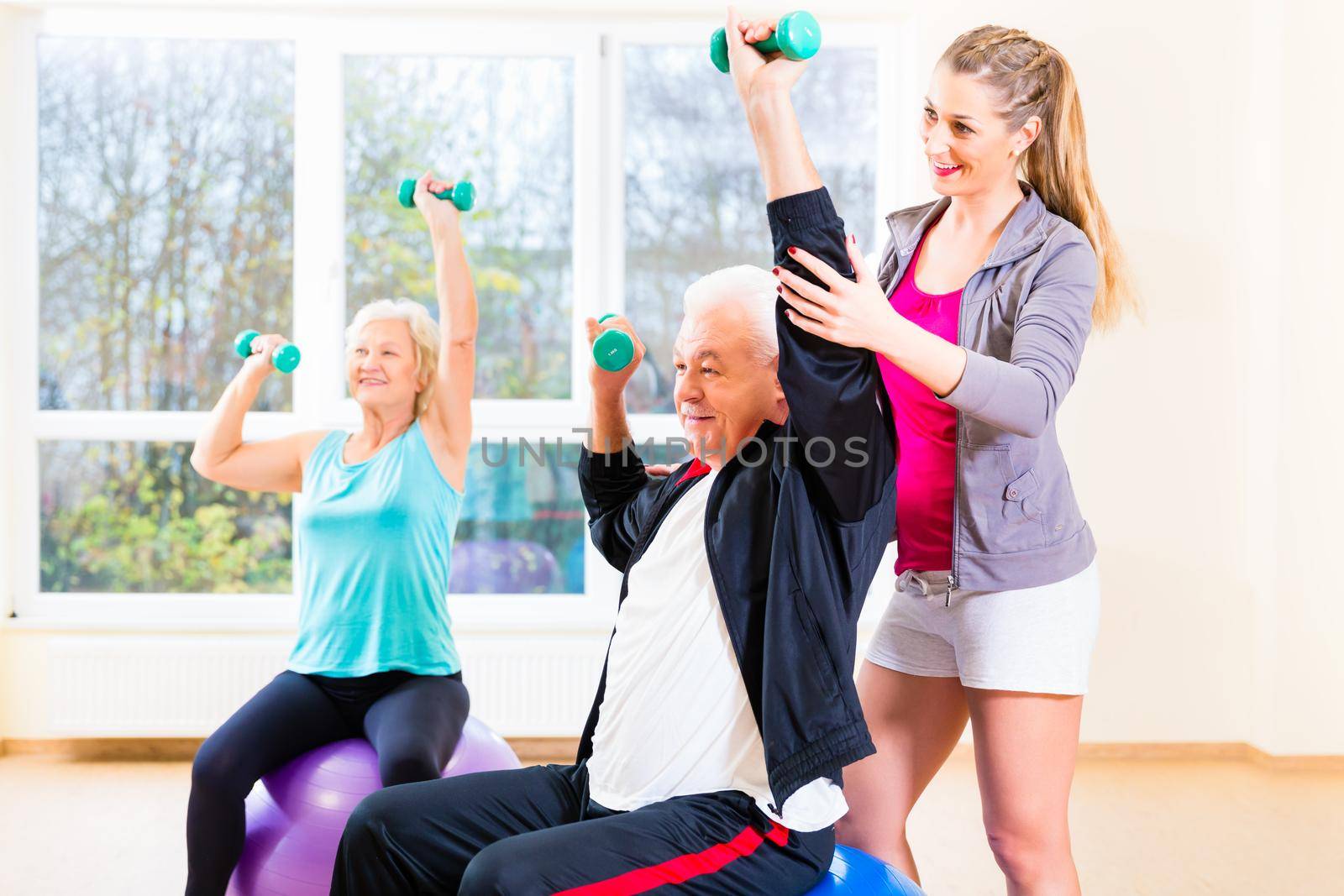 Physiotherapist coaching senior people exercising with dumbbells