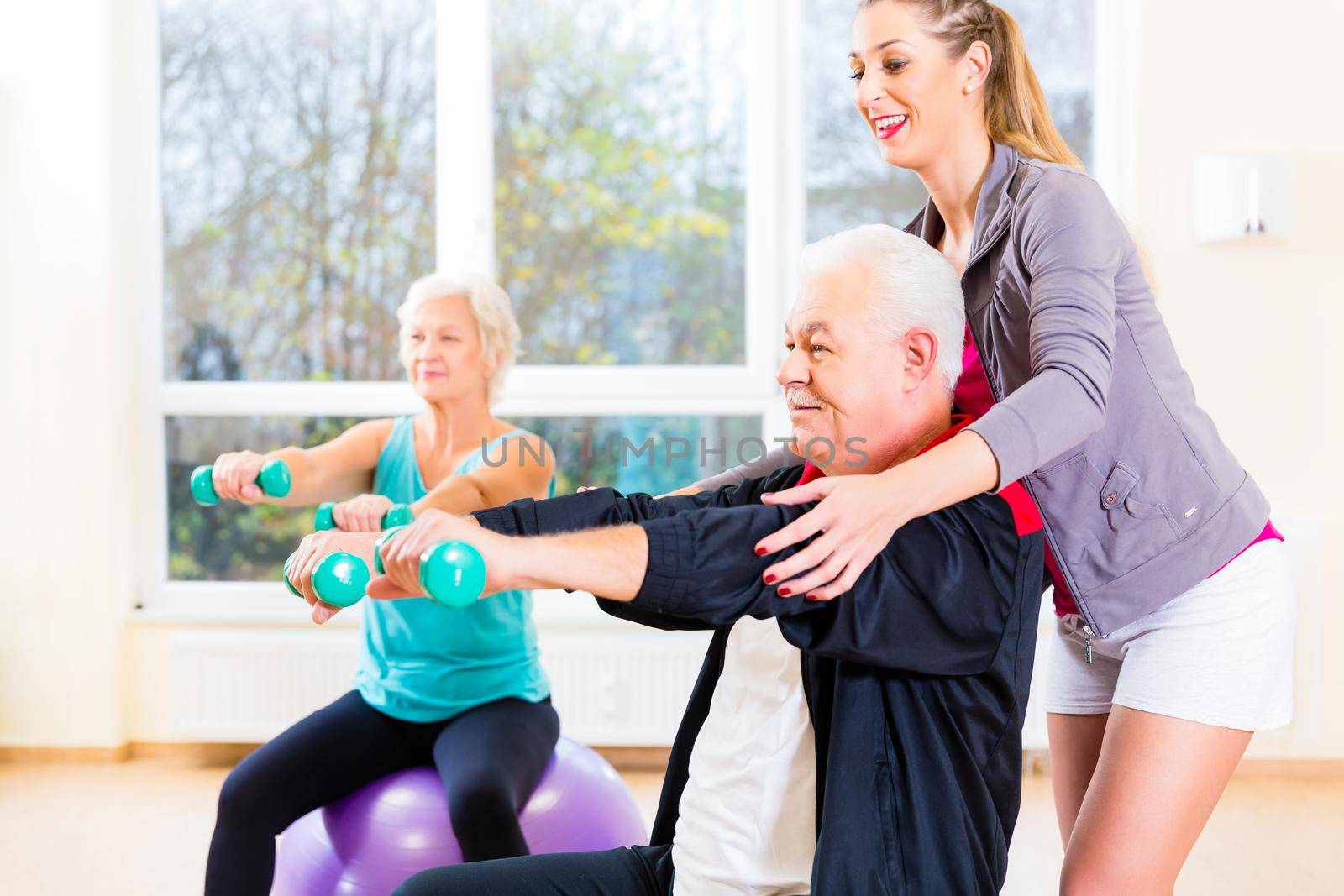 Physiotherapist coaching senior people exercising with dumbbells