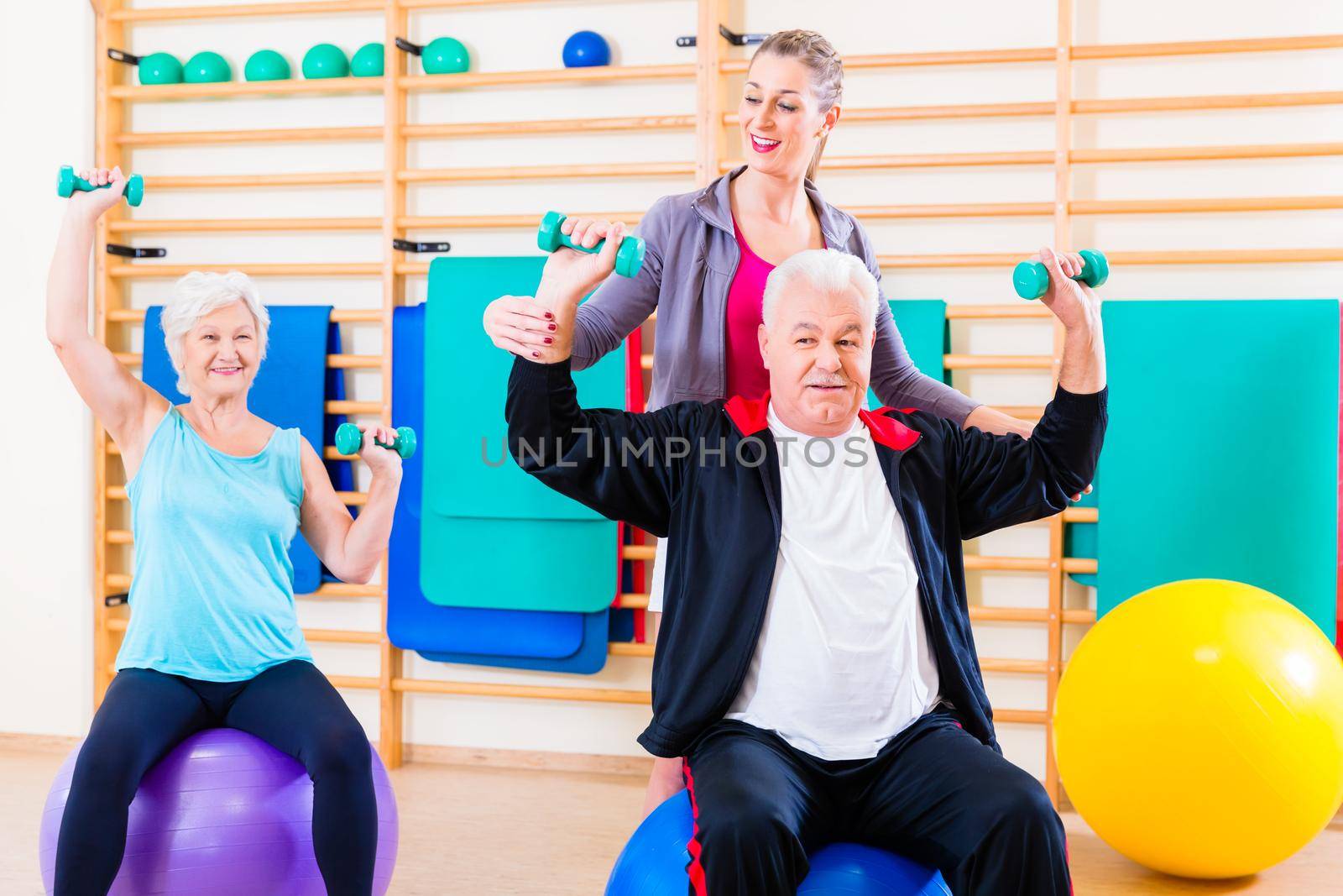 Physiotherapist coaching senior people exercising with dumbbells