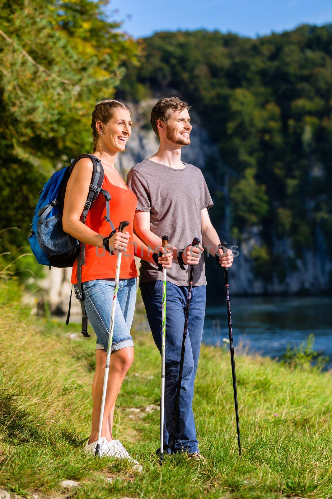 Man and woman hiking at river in summer for better fitness
