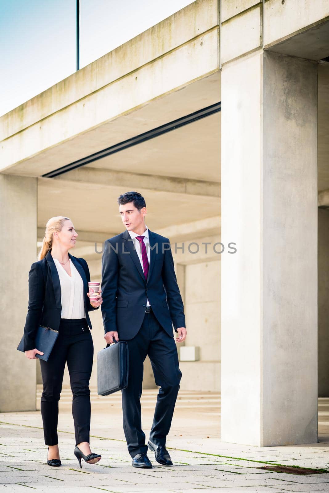 Business people walking to the next meeting in front of concrete architecture in city