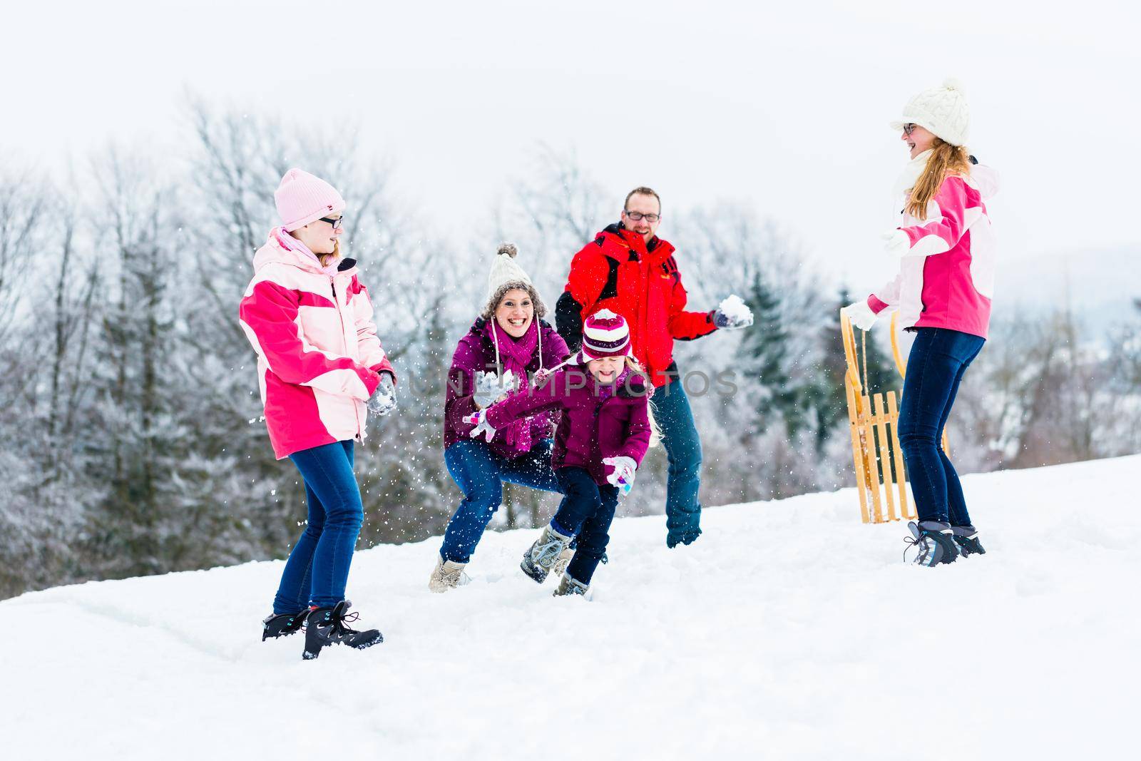 Family with kids having snowball fight in winter