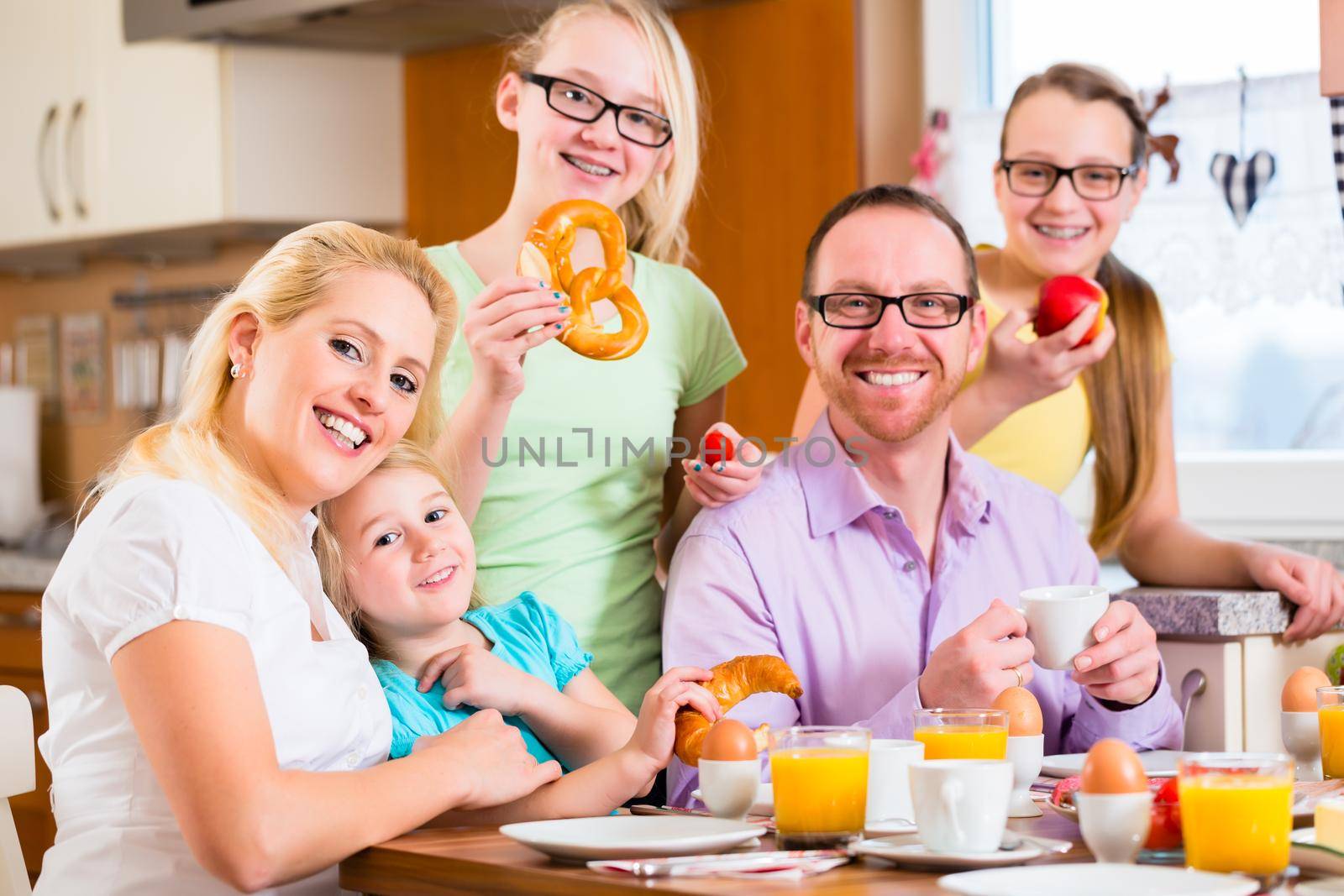 Family having joint breakfast in kitchen eating and drinking