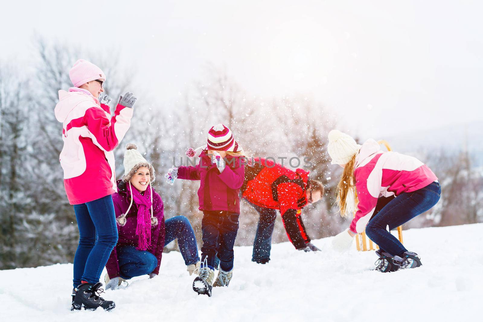 Family with kids having snowball fight in winter