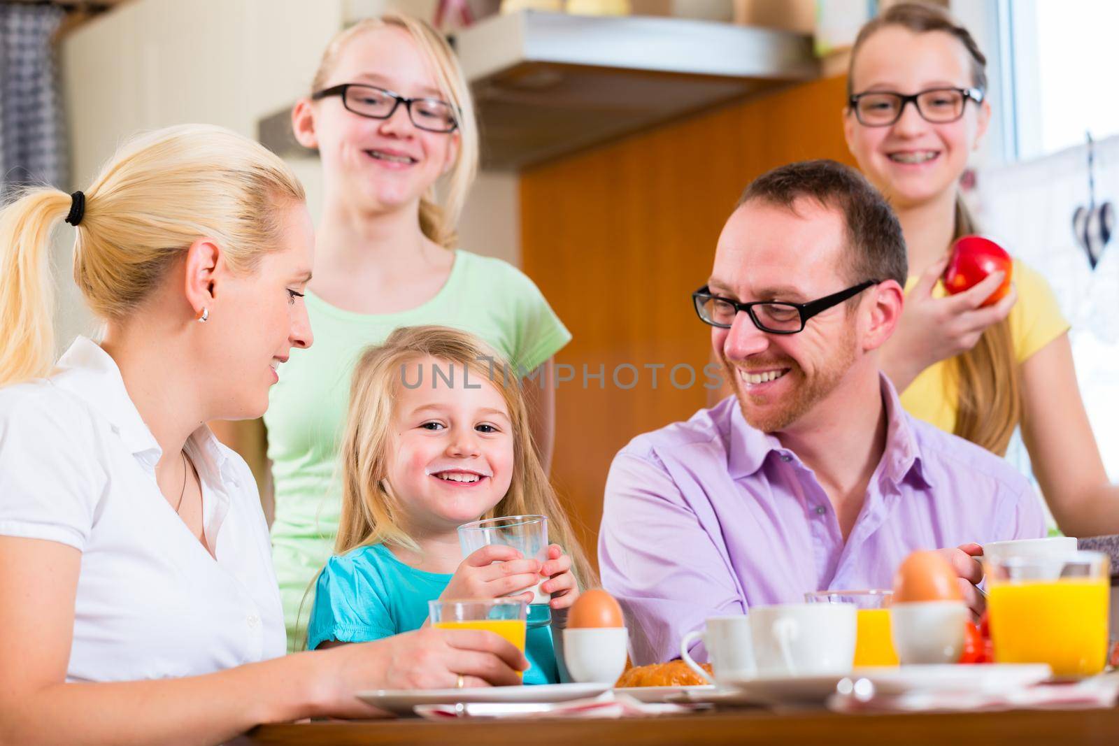 Family at home having breakfast in kitchen by Kzenon