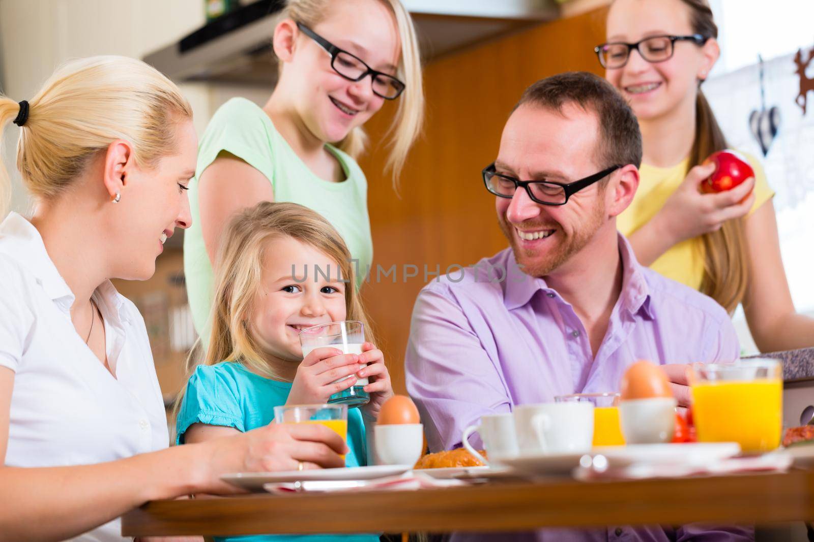 Family in their home having breakfast with eggs, fruit, coffee and juice