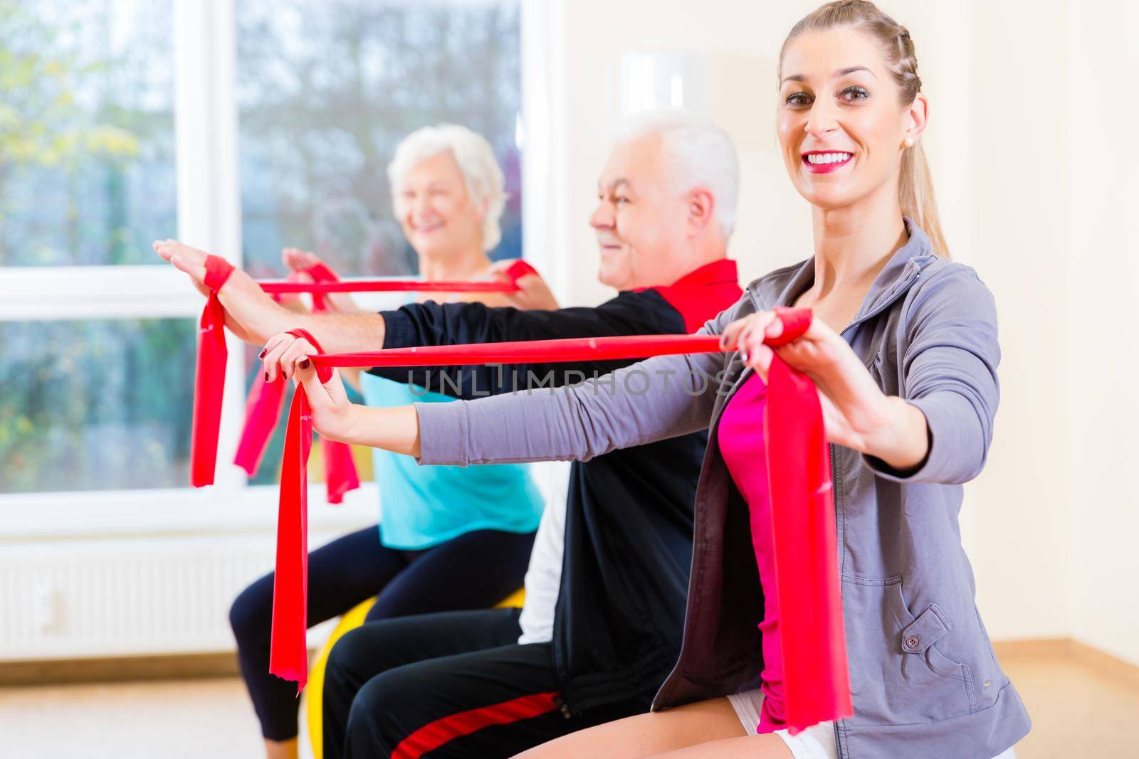 People, young and senior, at gym exercise with stretch band