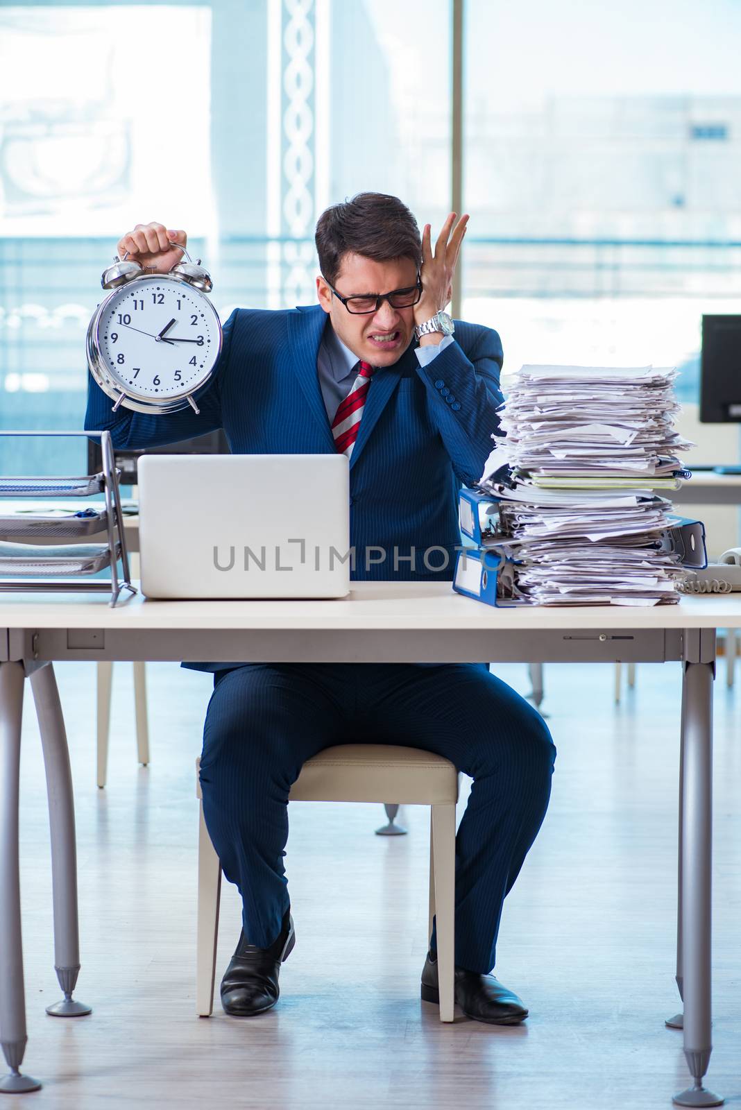 Businessman employee in urgency and deadline concept with alarm clock