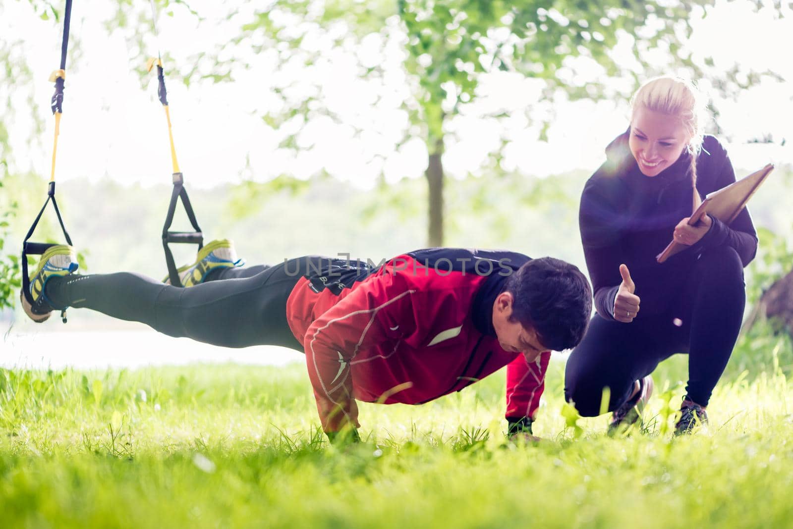 Sport couple outdoors with sling trainer