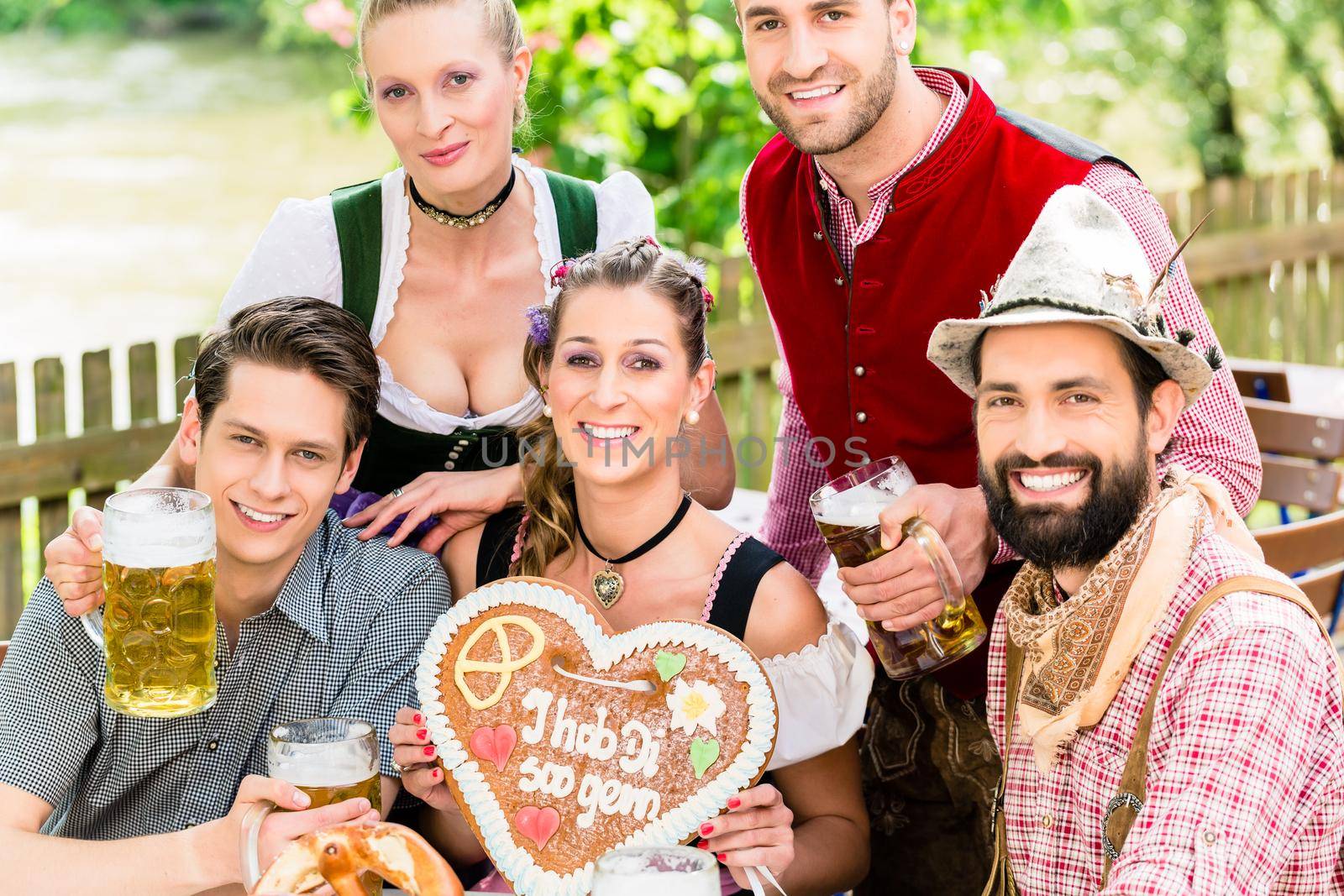 people with gingerbread heart in beer garden drinking beer in summer