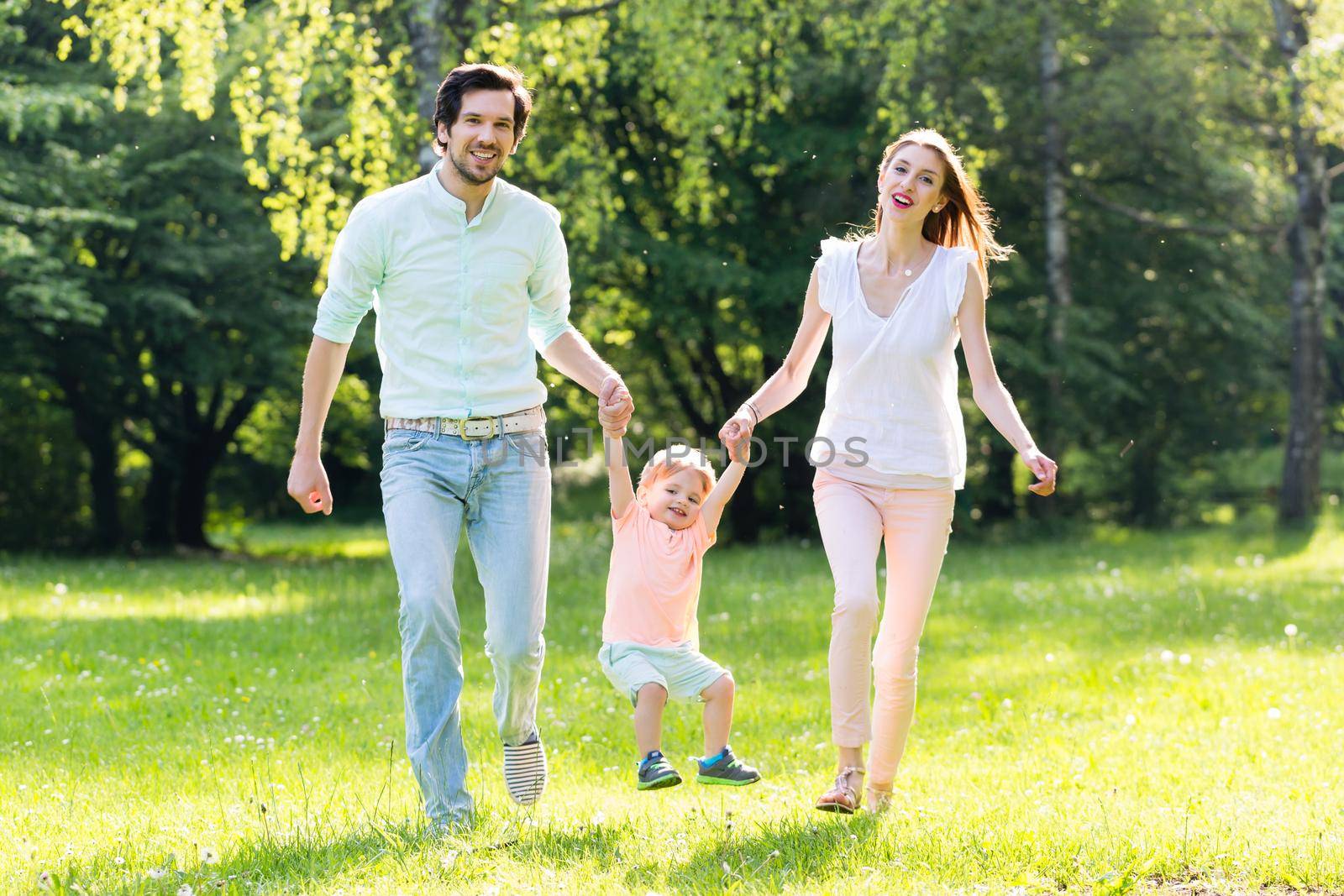 Family having walk together in summer holding hands and letting the little boy fly