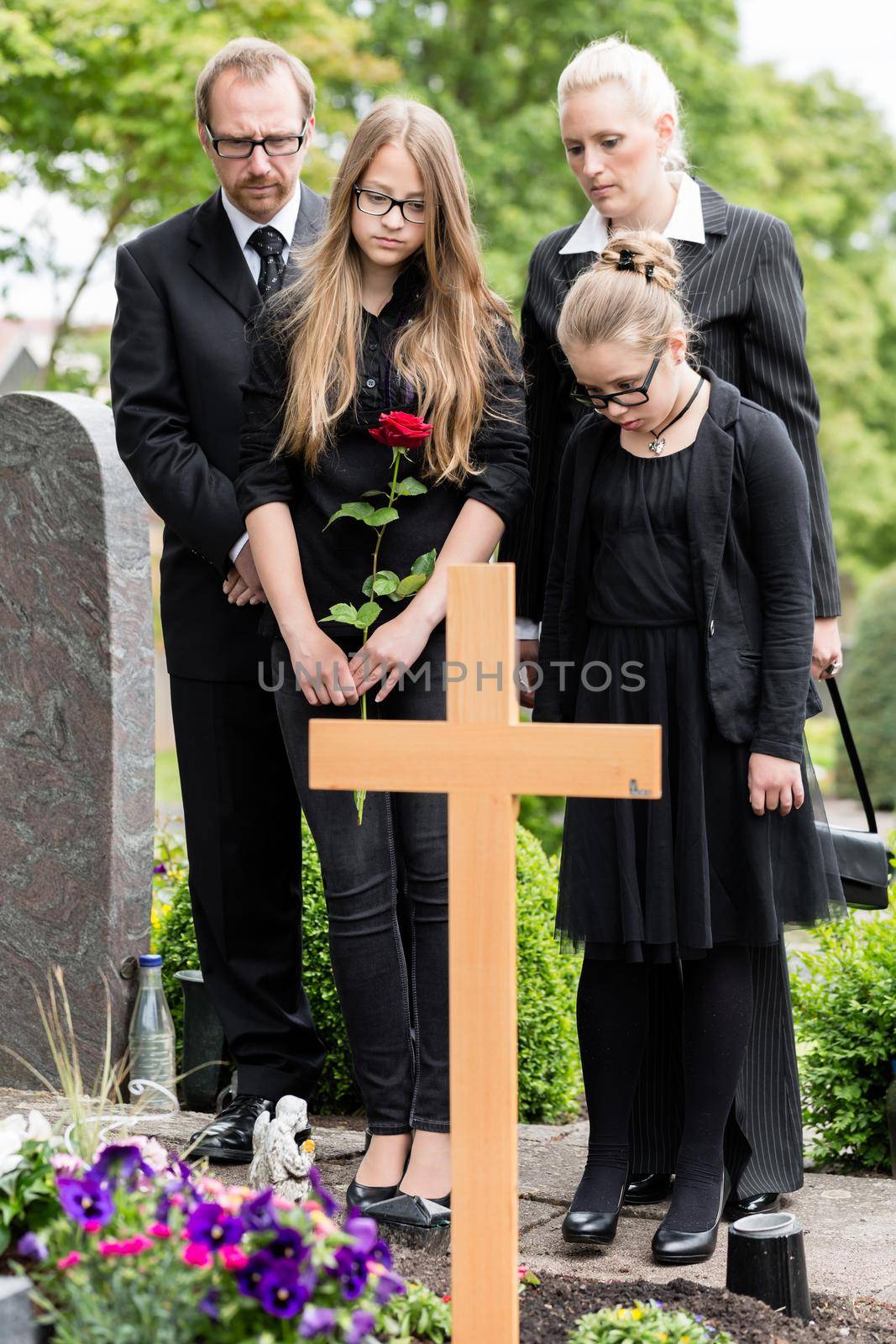 Family mourning at grave on graveyard or cemetery