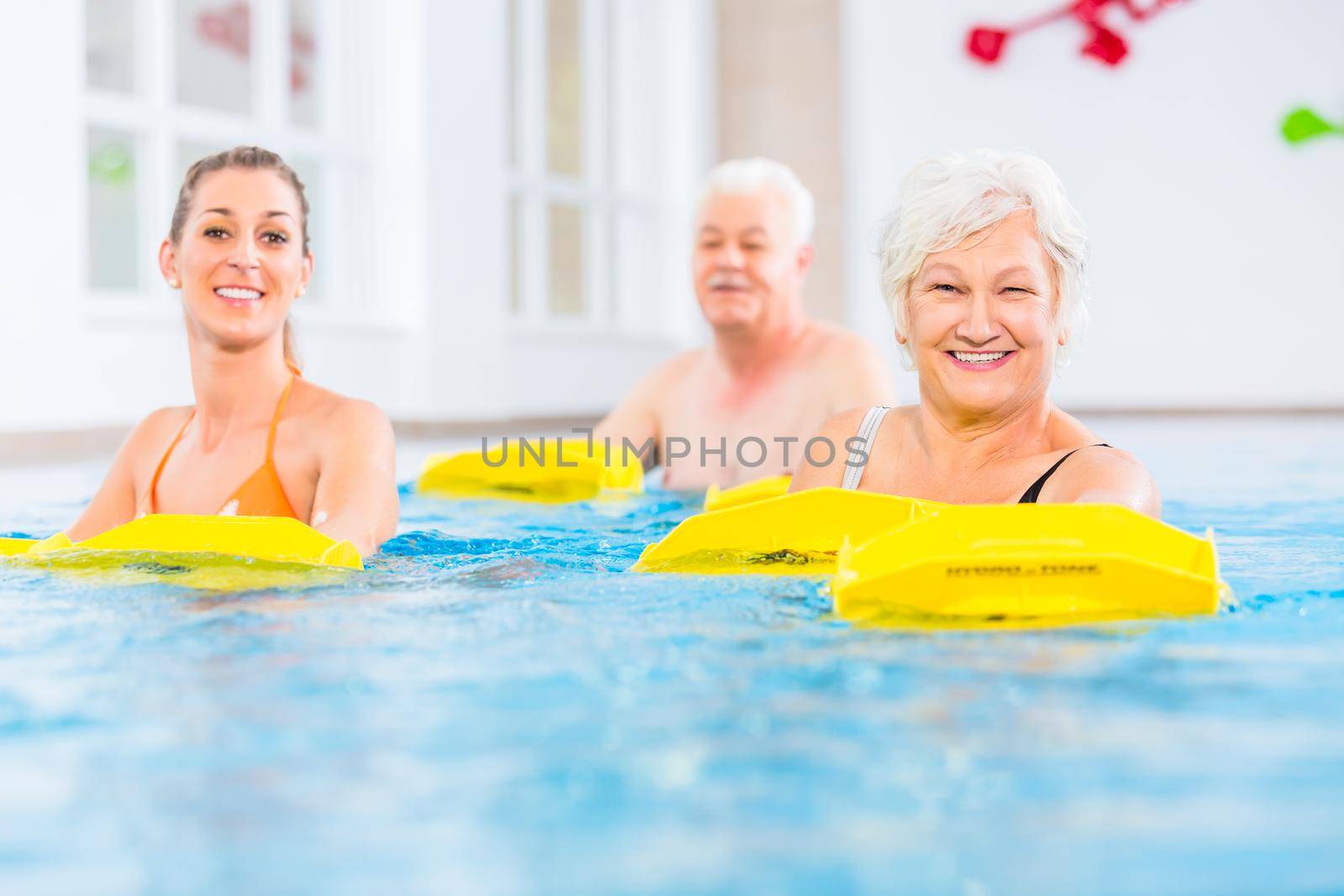 Senior and young people in water gymnastics with resistance device