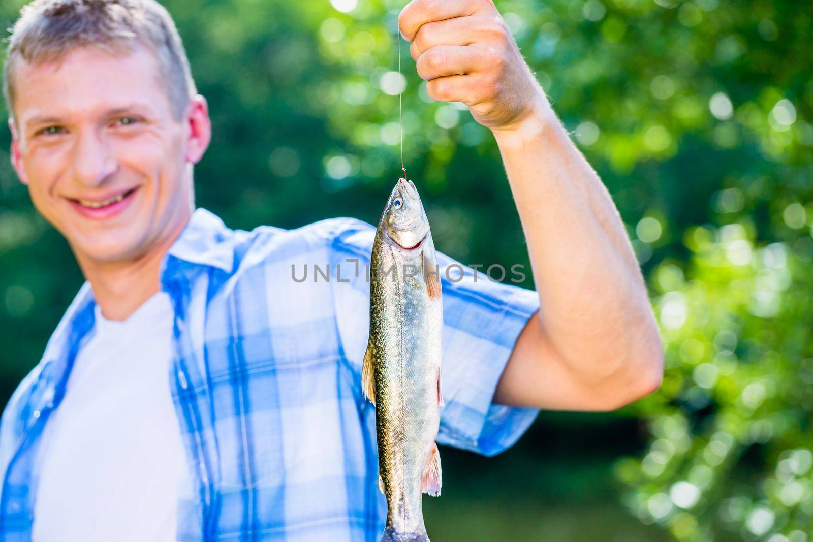 Sport fisherman showing catch dangling from fishing rod by Kzenon