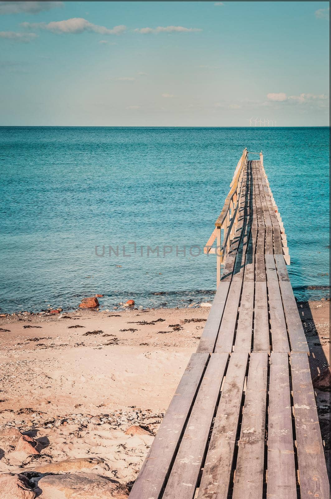 Wooden bridge on a tropical island, transparent sea and blue sky, advertising for tourism