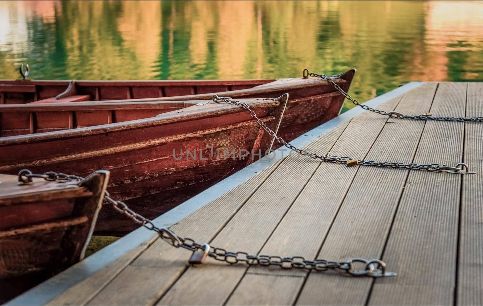 Boat chains on the dock, close up of boat chains, two wooden boats on the dock, Rope knots on the teak deck of a vintage wooden sailboat yacht by isaiphoto