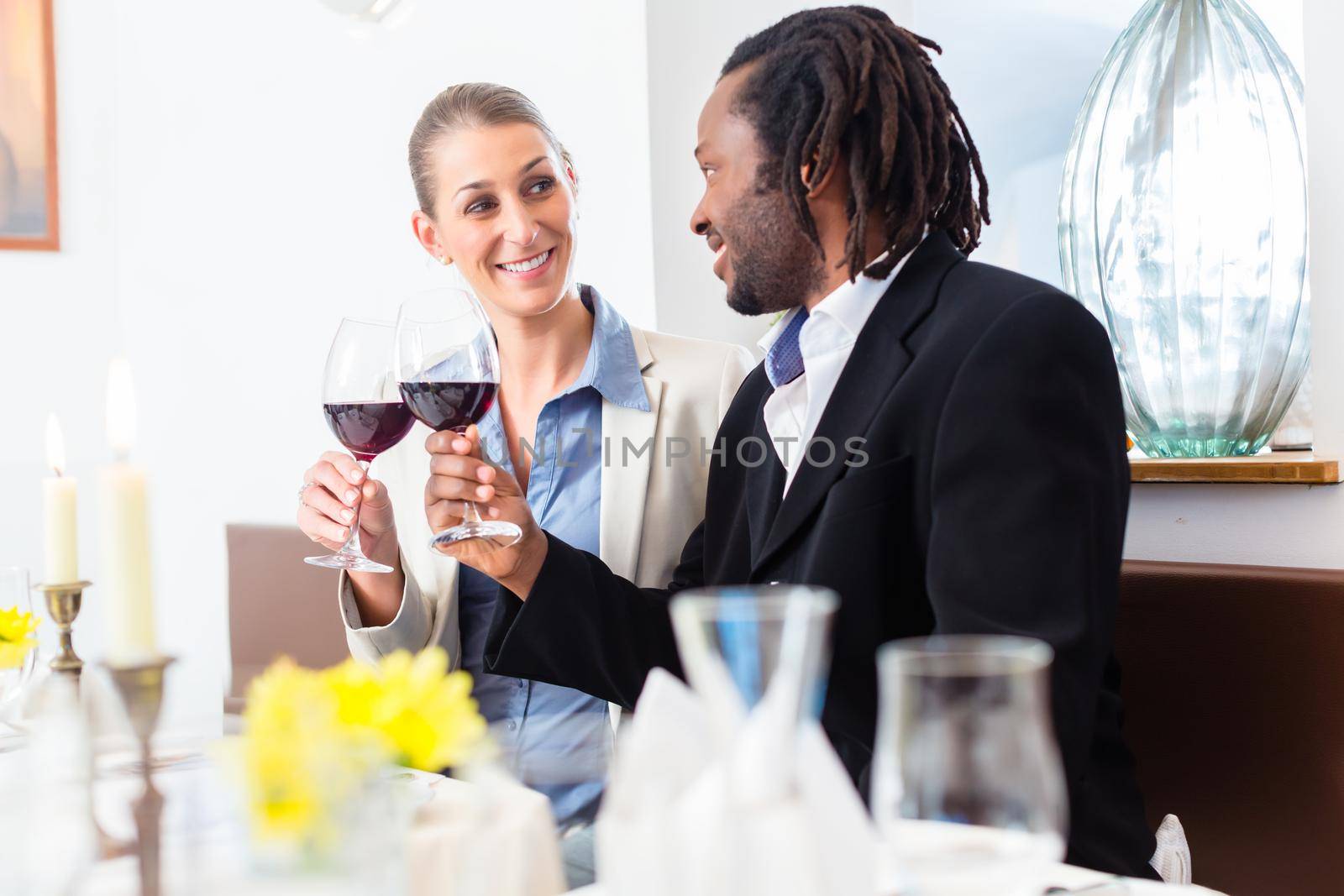 Business people, caucasian woman and african american man, toasting on deal with wine