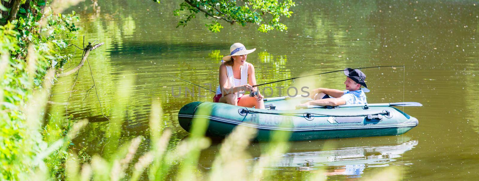 Couple in boat on pond or lake fishing by Kzenon