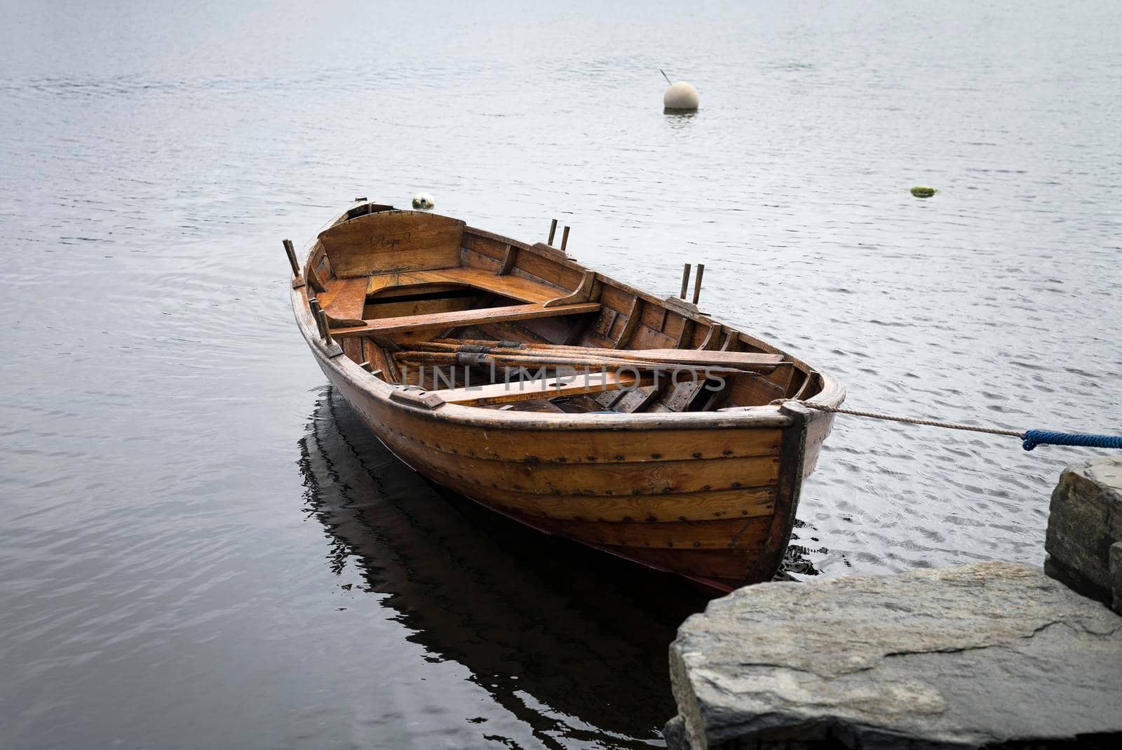 A boat on the lake near a dock, Sunset over the lake in the village. View from a wooden bridge with a boat aside