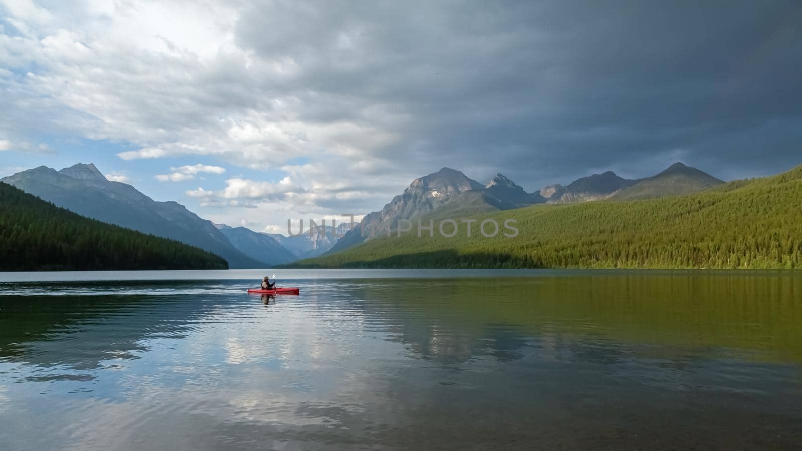 Man paddling on Bowman Lake in Glacier National Park, A terrific place to go camping, hiking, or fishing in Montana.
