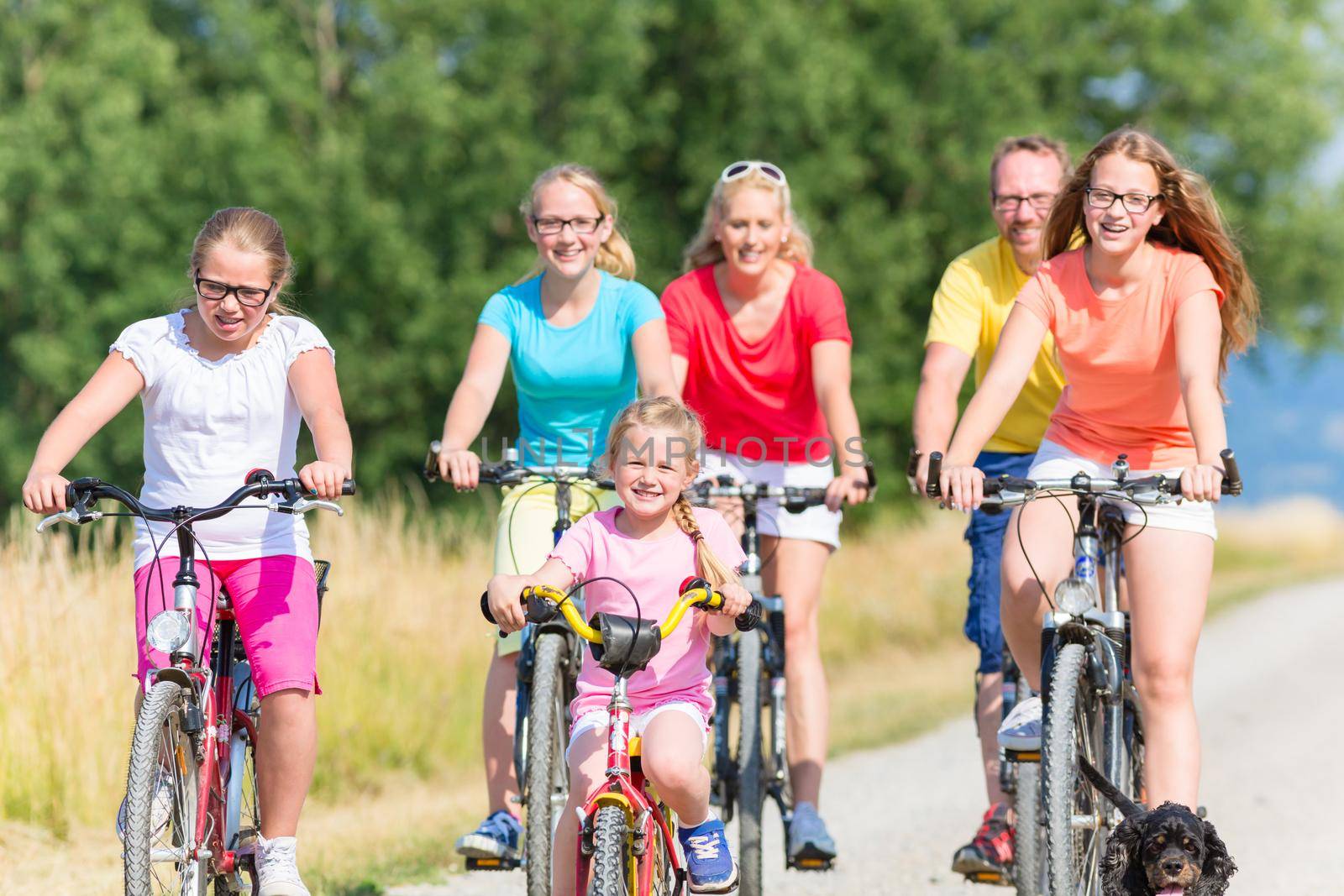 Family on bikes riding down dirt path, mother, father and children together