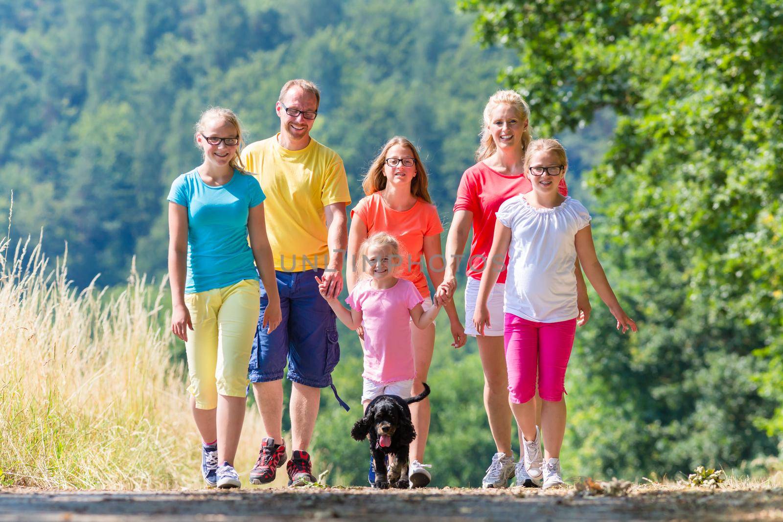 Family having walk on path in the woods by Kzenon