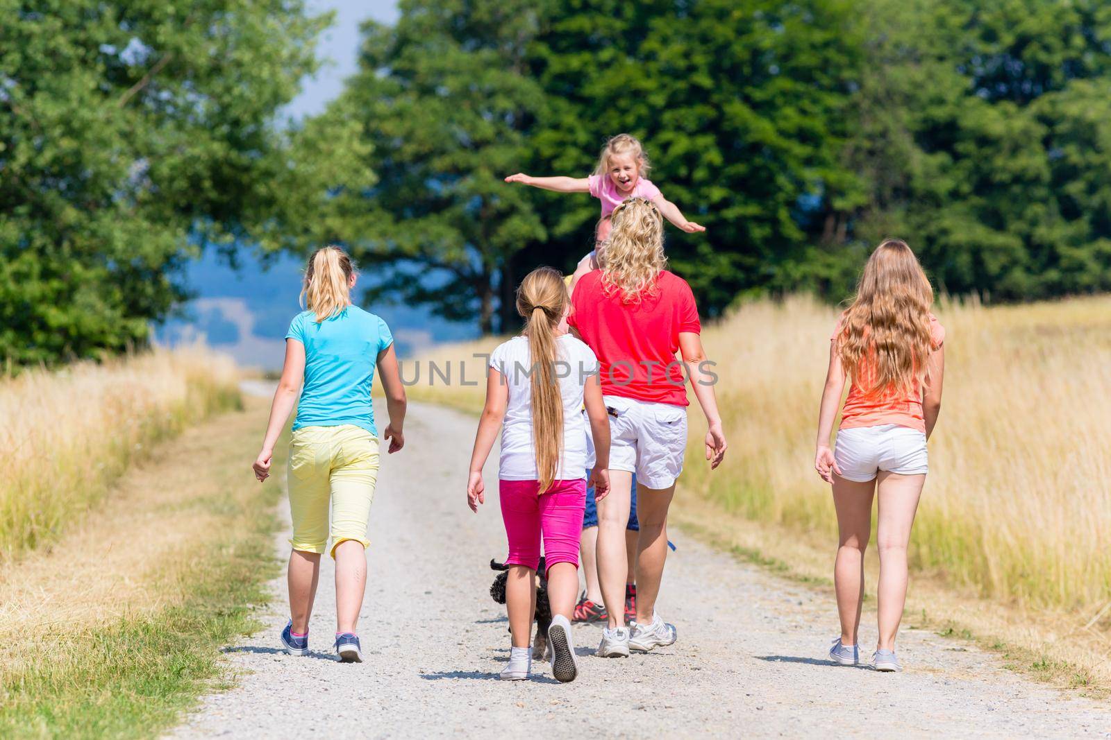 Family, mother father and kids, having walk in summer on dirt path