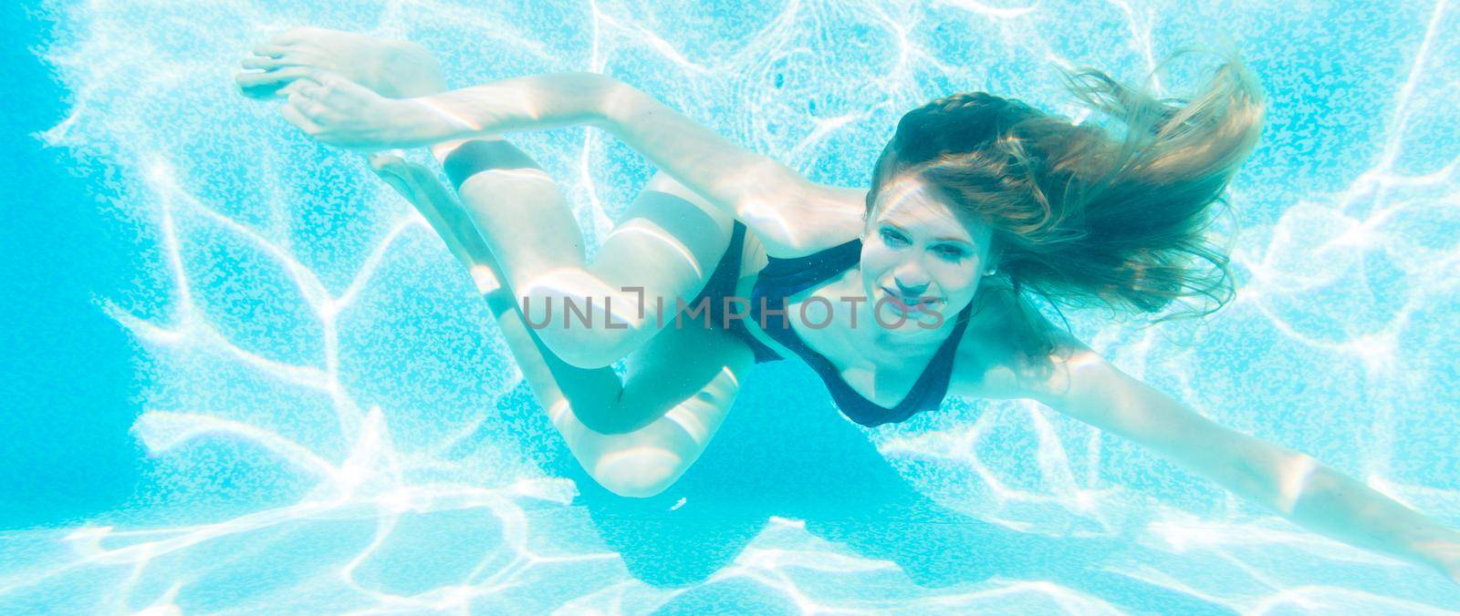 Happy girl diving underwater in swimming pool