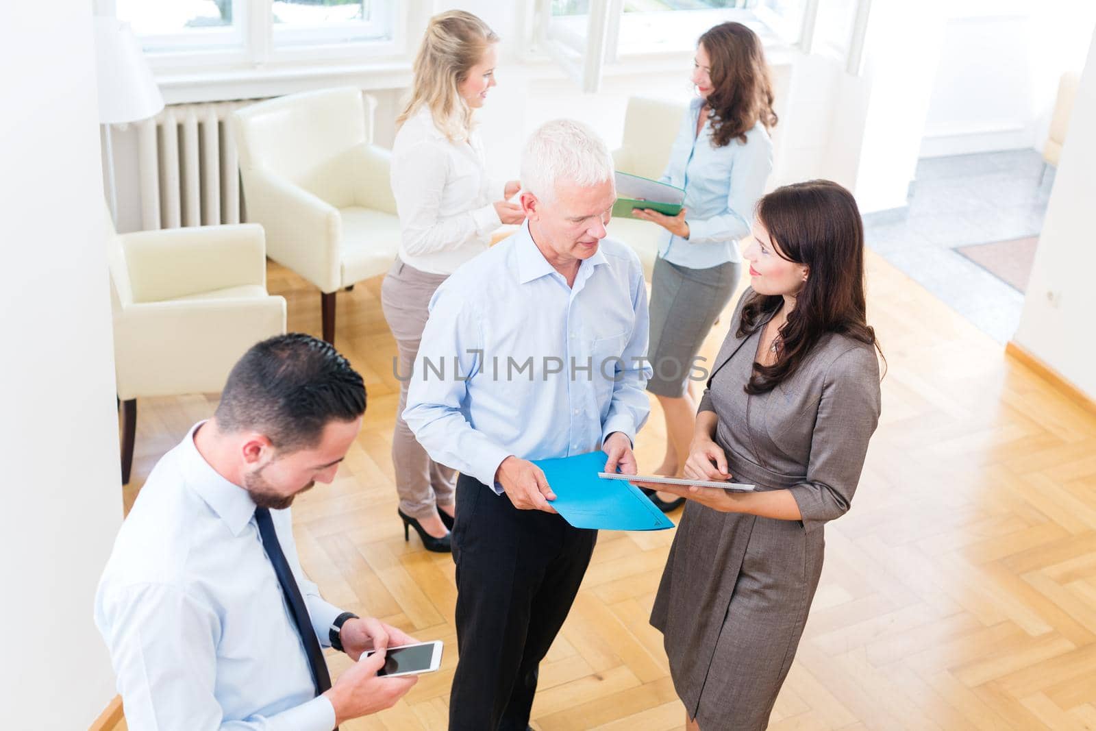 Group of business people standing in office, discussing and working together