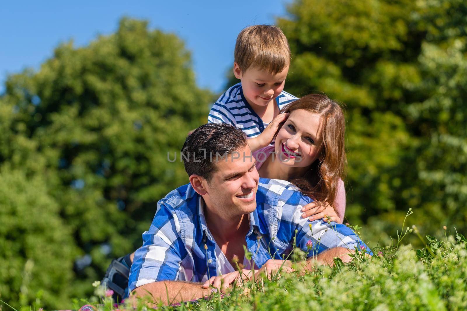 Family lying in grass on top of each other by Kzenon