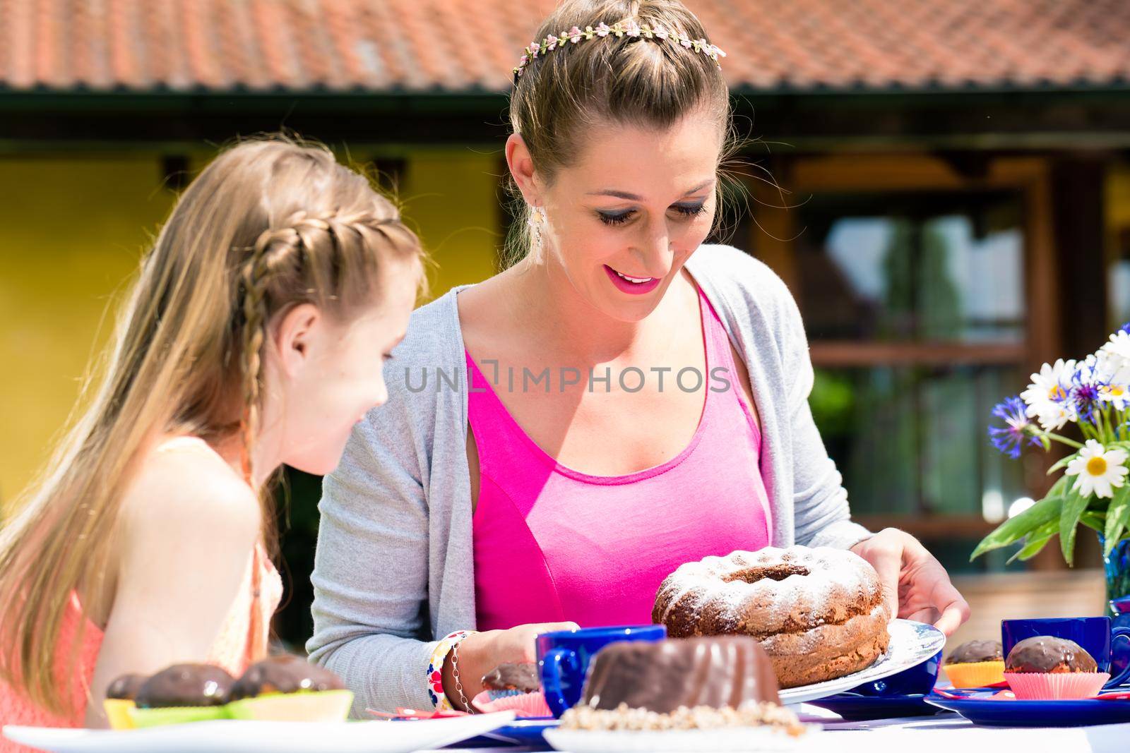 Mother cutting the cake for the family while having coffee time outdoors