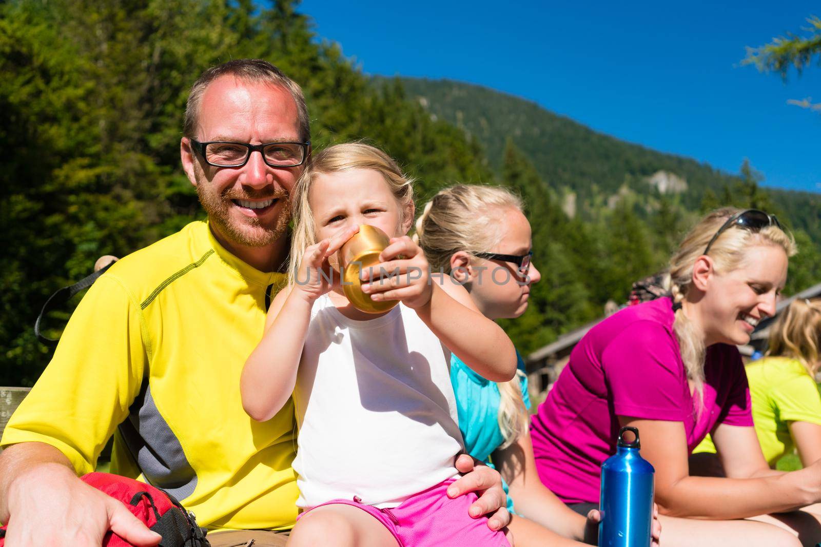 Family having break from hiking in the summer mountains