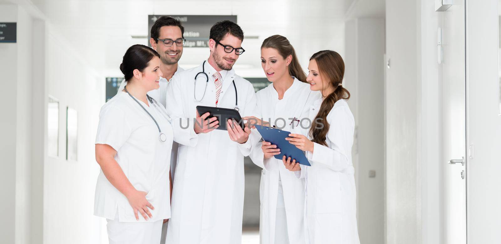 Team of doctors in hospital working on documents by Kzenon