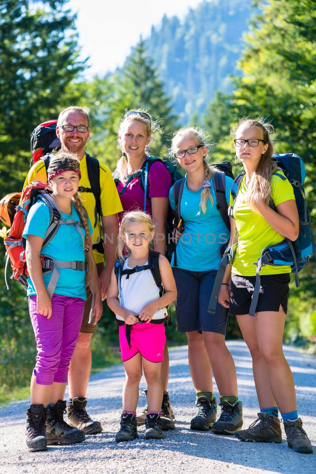 Family with four kids hiking in the mountains standing on path