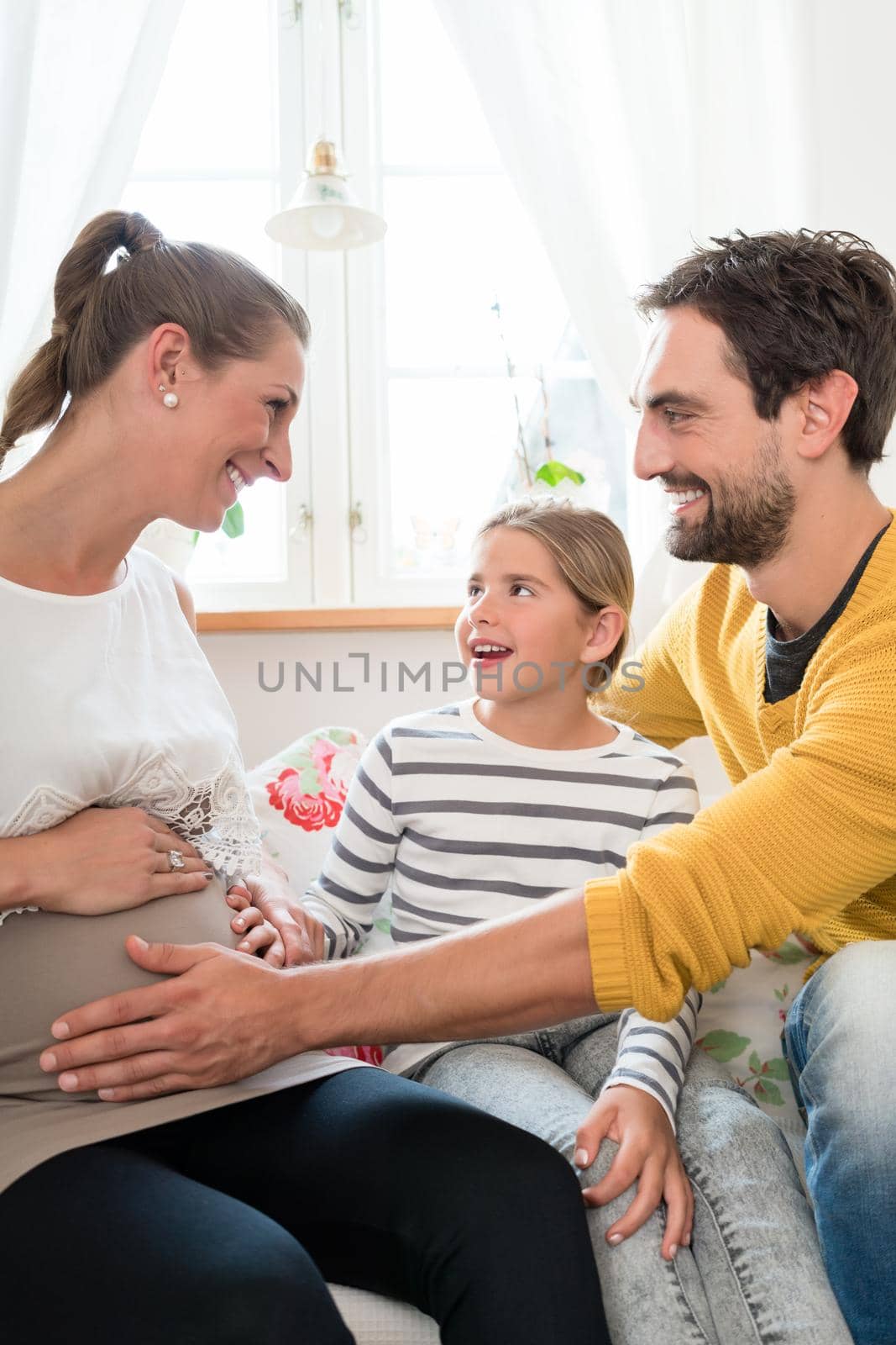 Little family is happy about pregnancy of mother, father touching belly