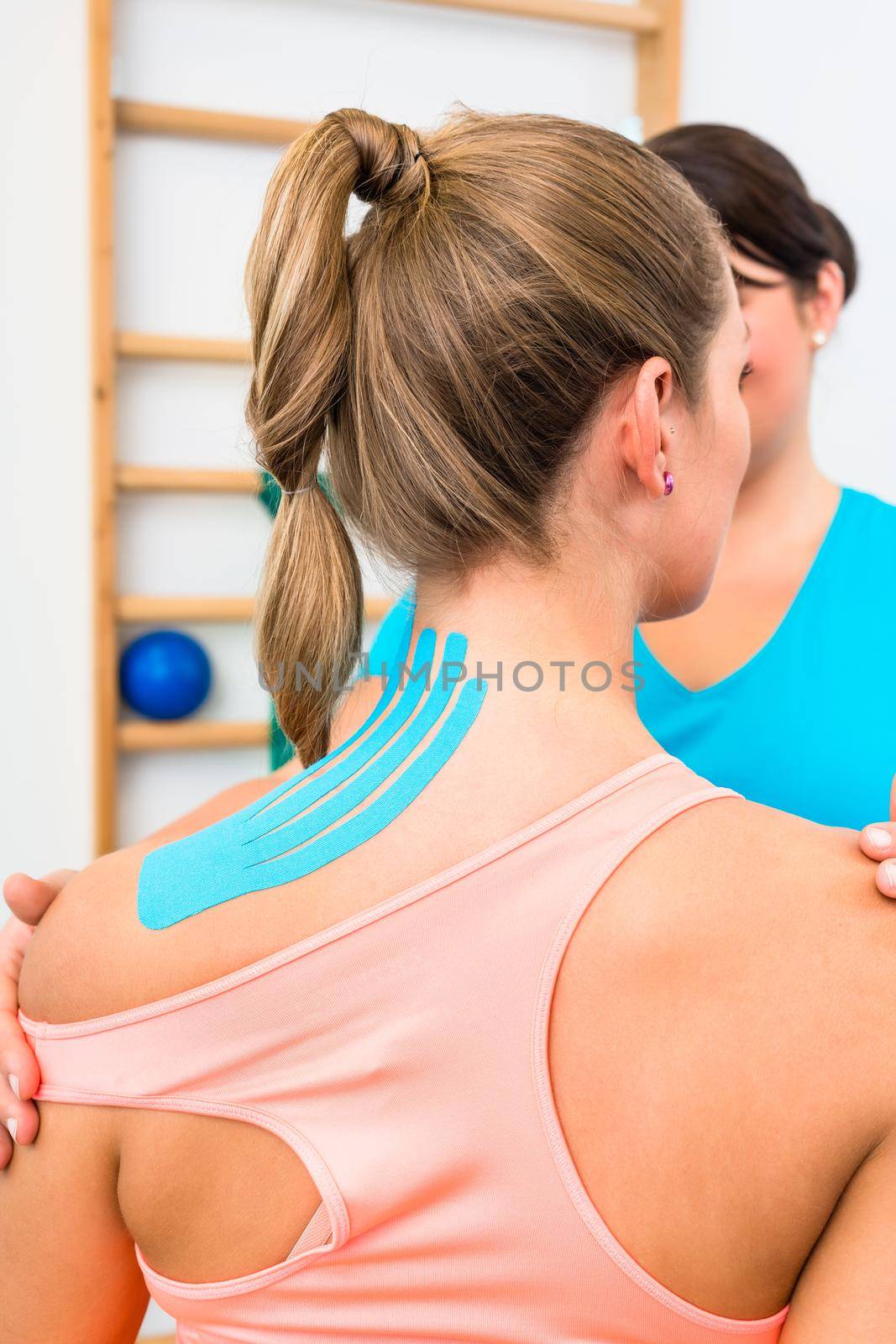 Woman from behind with Kinesio tape on shoulder during physiotherapy