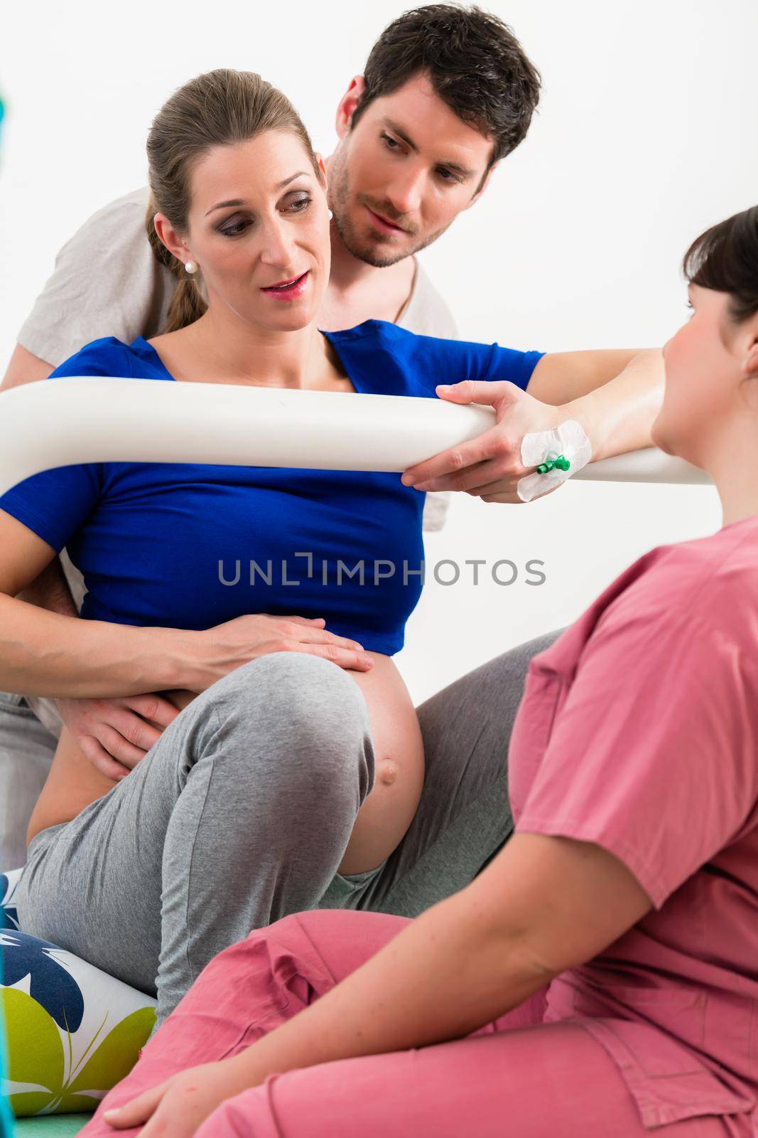 Woman laboring in delivery room with nurse and husband before birth