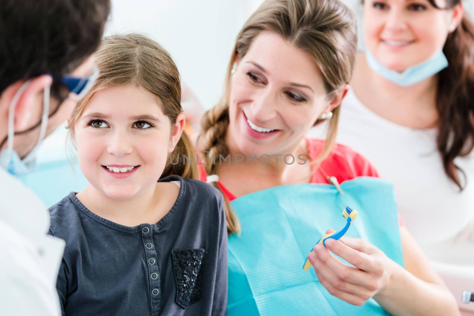 Dentist and his assistant with pregnant woman and child in surgery